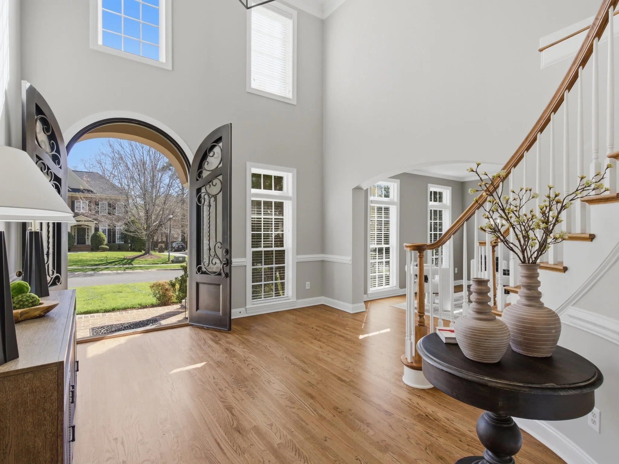 Staged two-story foyer with iron front door and curved staircase