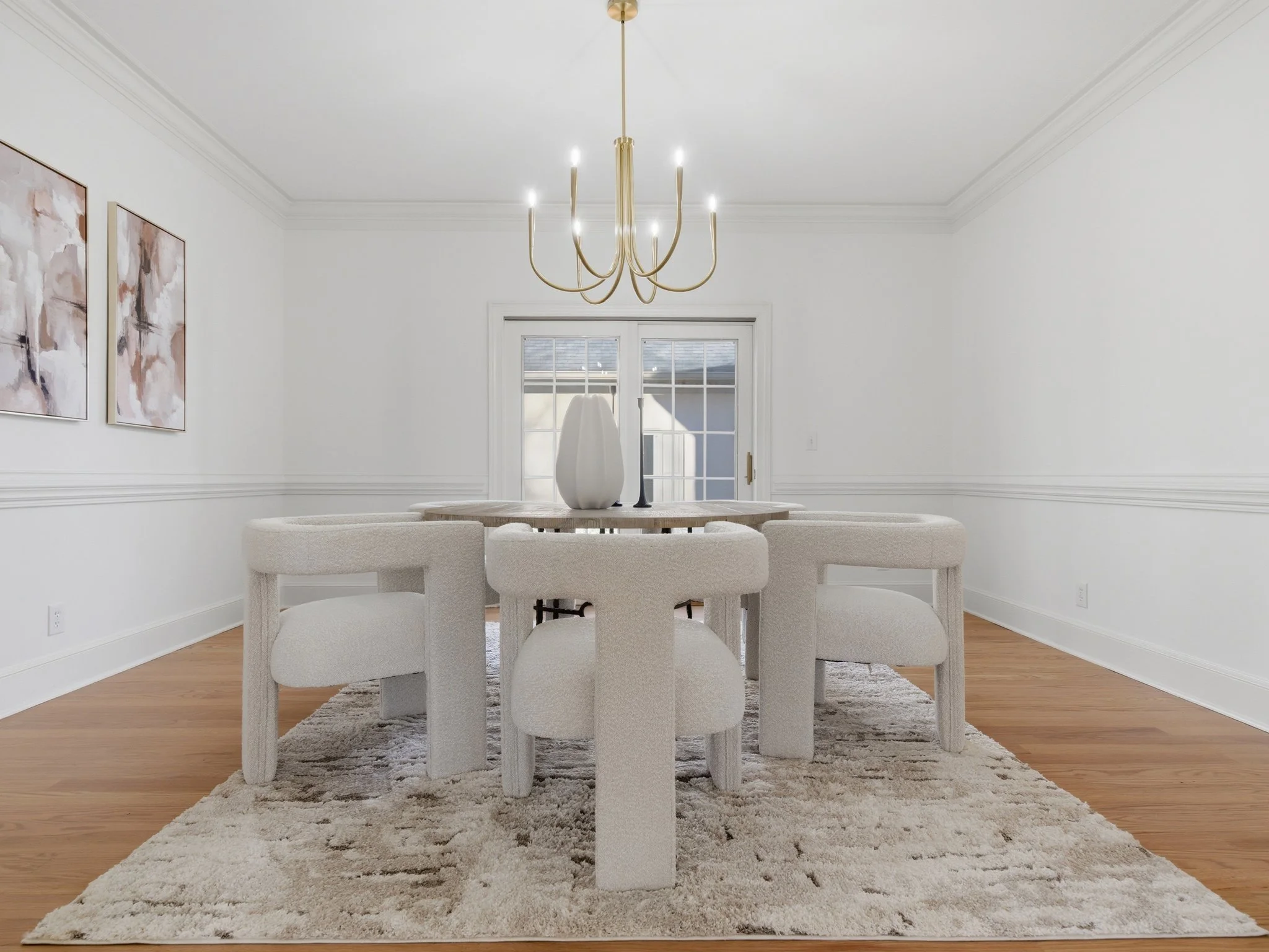 Staged dining room with boucle chairs and brass chandelier