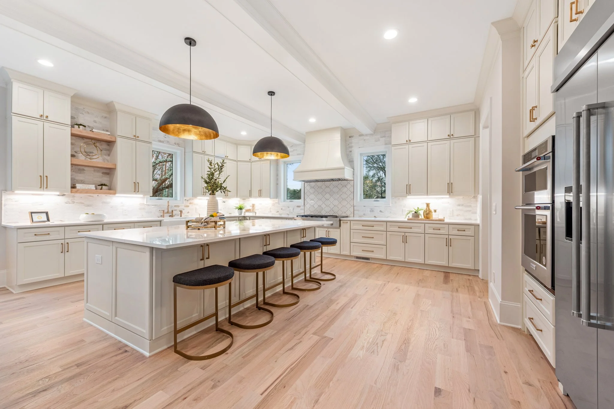 Staged kitchen with large island and black dome pendants