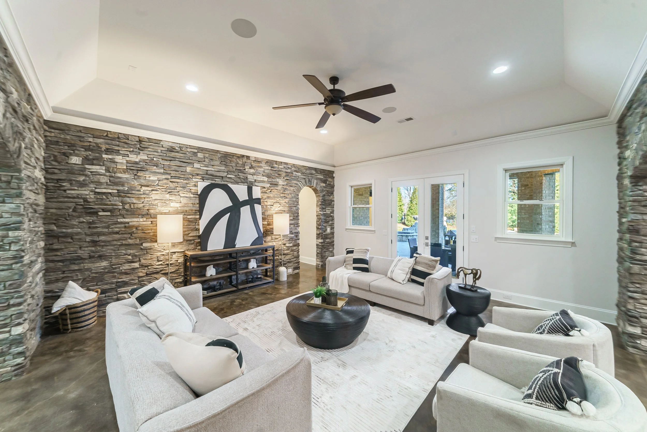 Staged rec room with French doors and stacked stone walls
