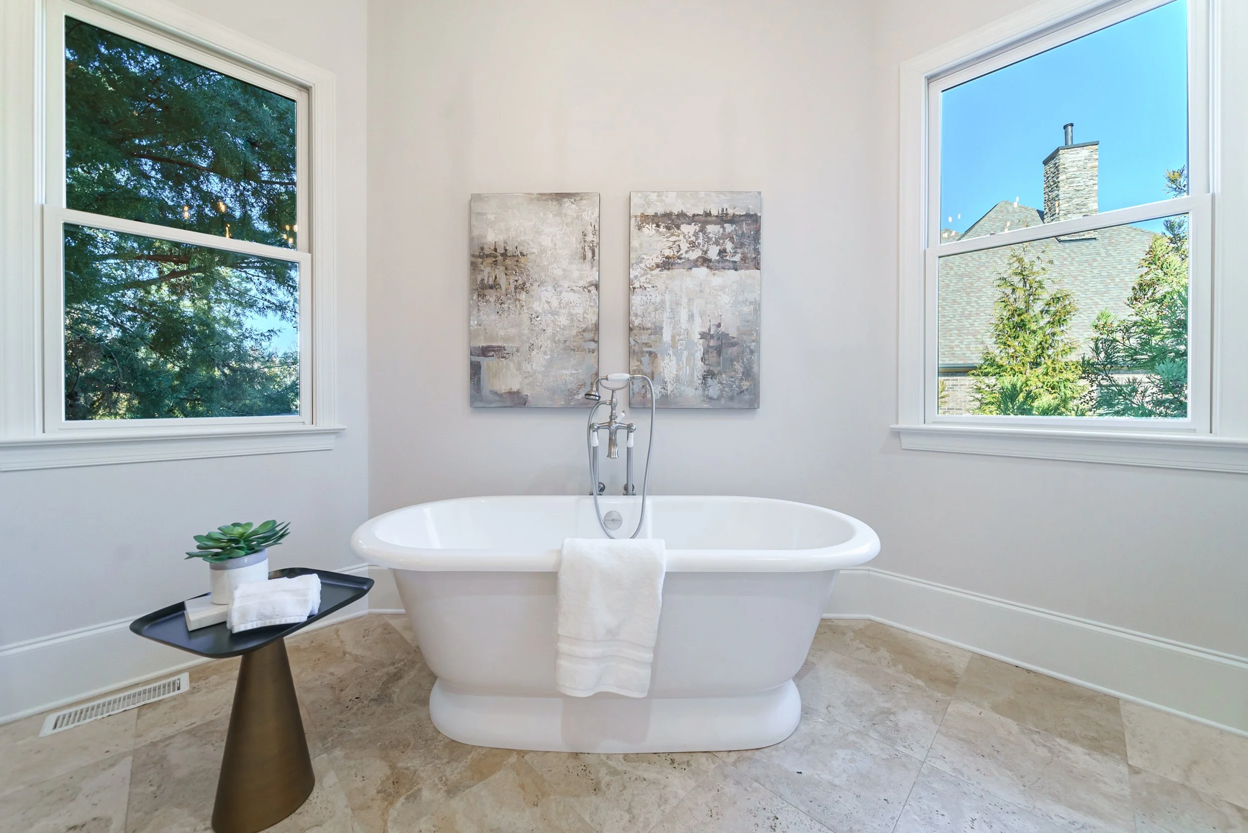 Staged primary bathroom with freestanding tub and dual windows