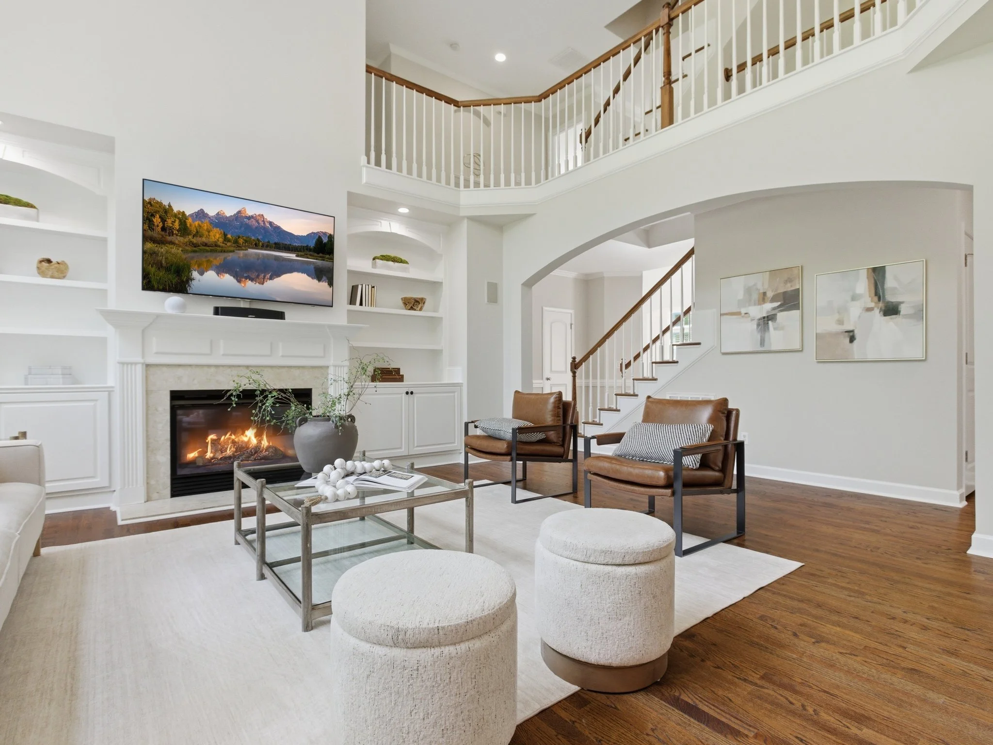 Staged living room with fireplace and view to staircase