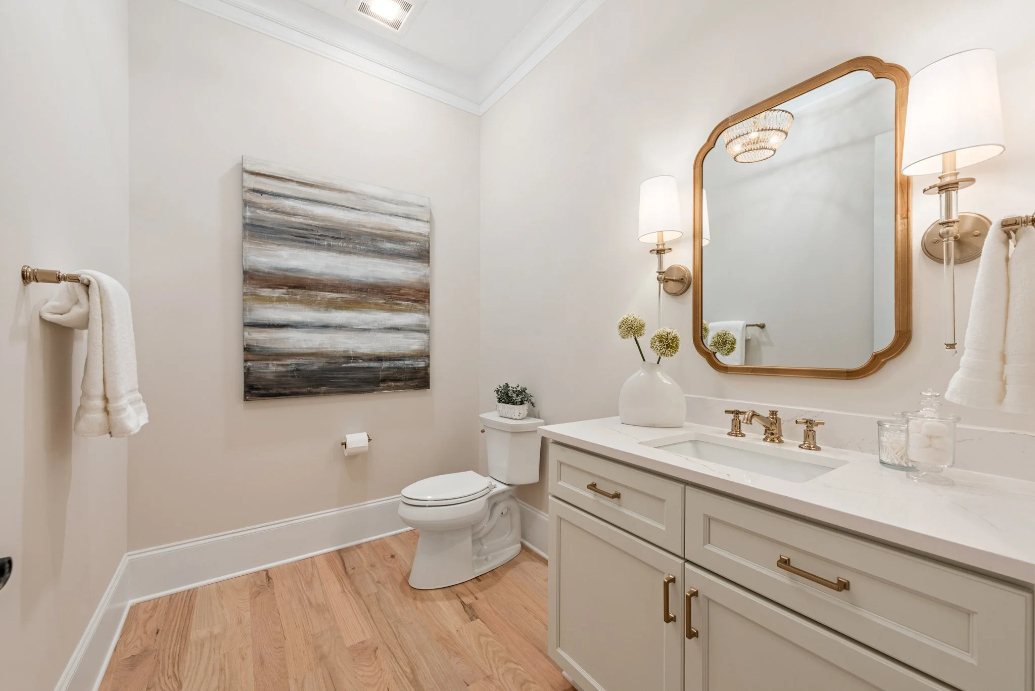 Staged powder bathroom with brass fixtures and gold mirror