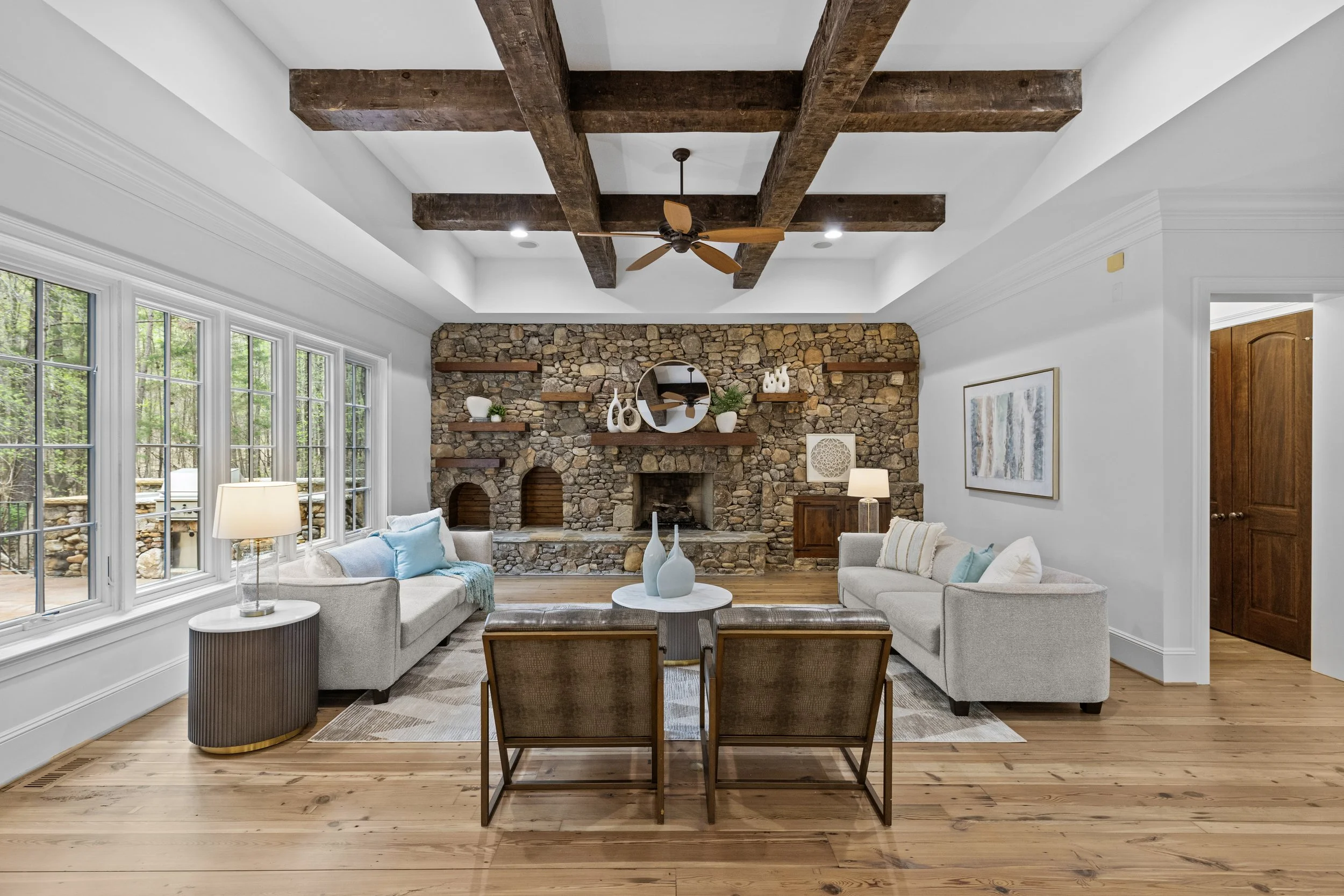 Staged living room with stacked stone fireplace and wood beam ceiling
