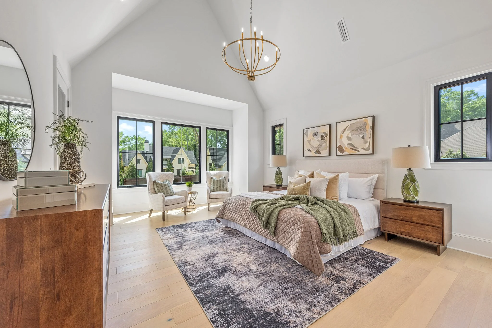 Staged primary bedroom with vaulted ceiling and bay window