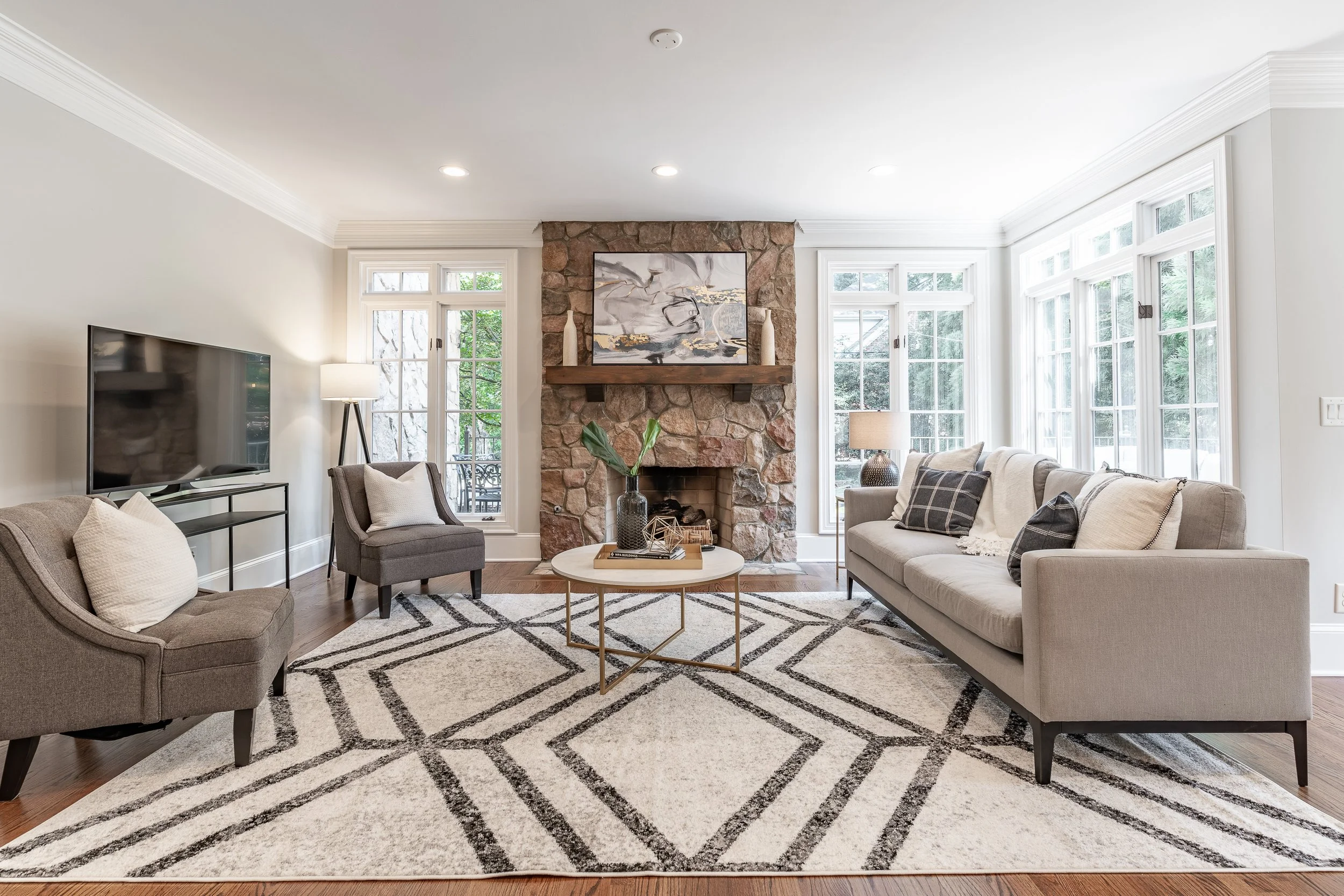 Staged living room with stone fireplace and patterned rug