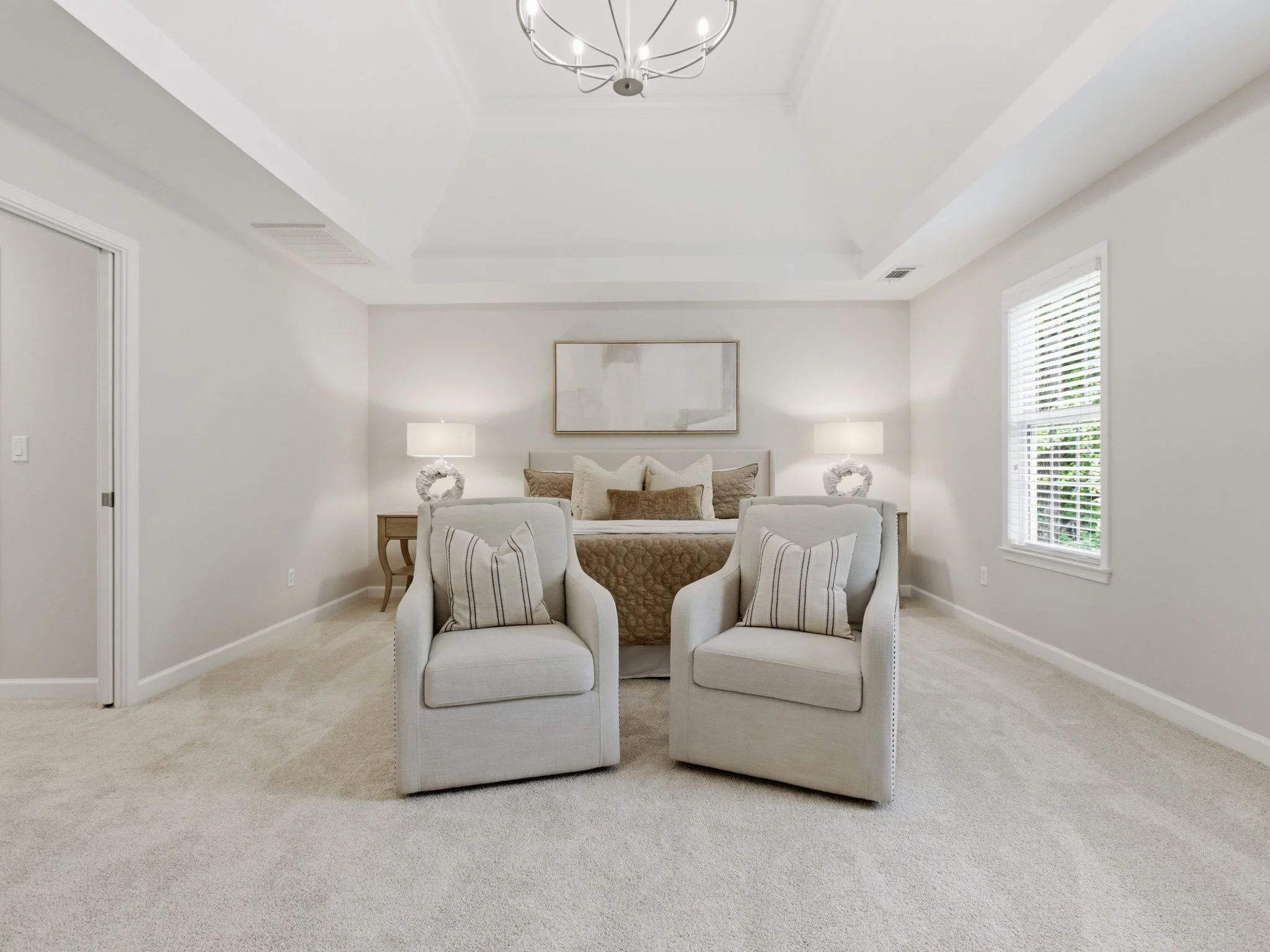 Staged primary bedroom with matching swivel chairs
