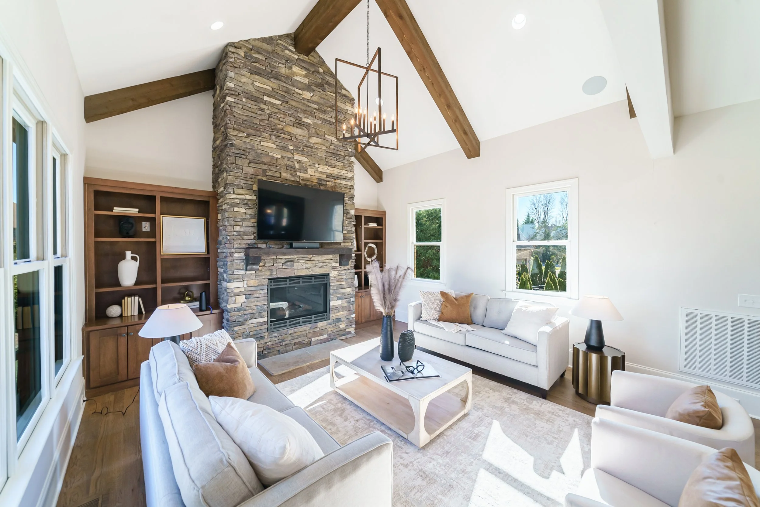 Staged living room with stone fireplace and wood beam ceiling