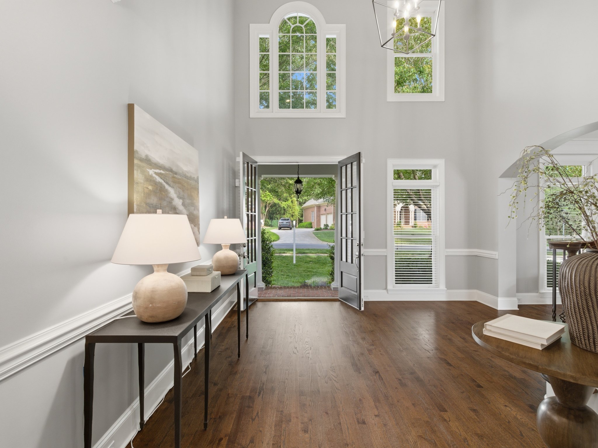 Staged foyer with open front door and console tables 