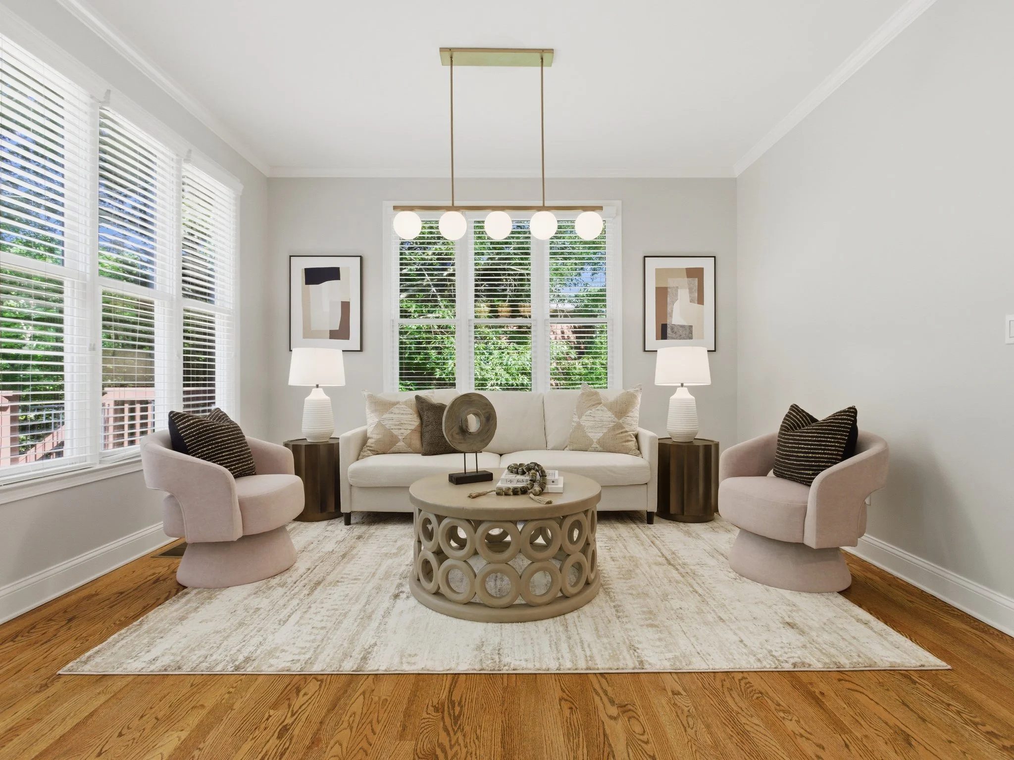 Staged sitting room with blush swivel chairs and ring coffee table