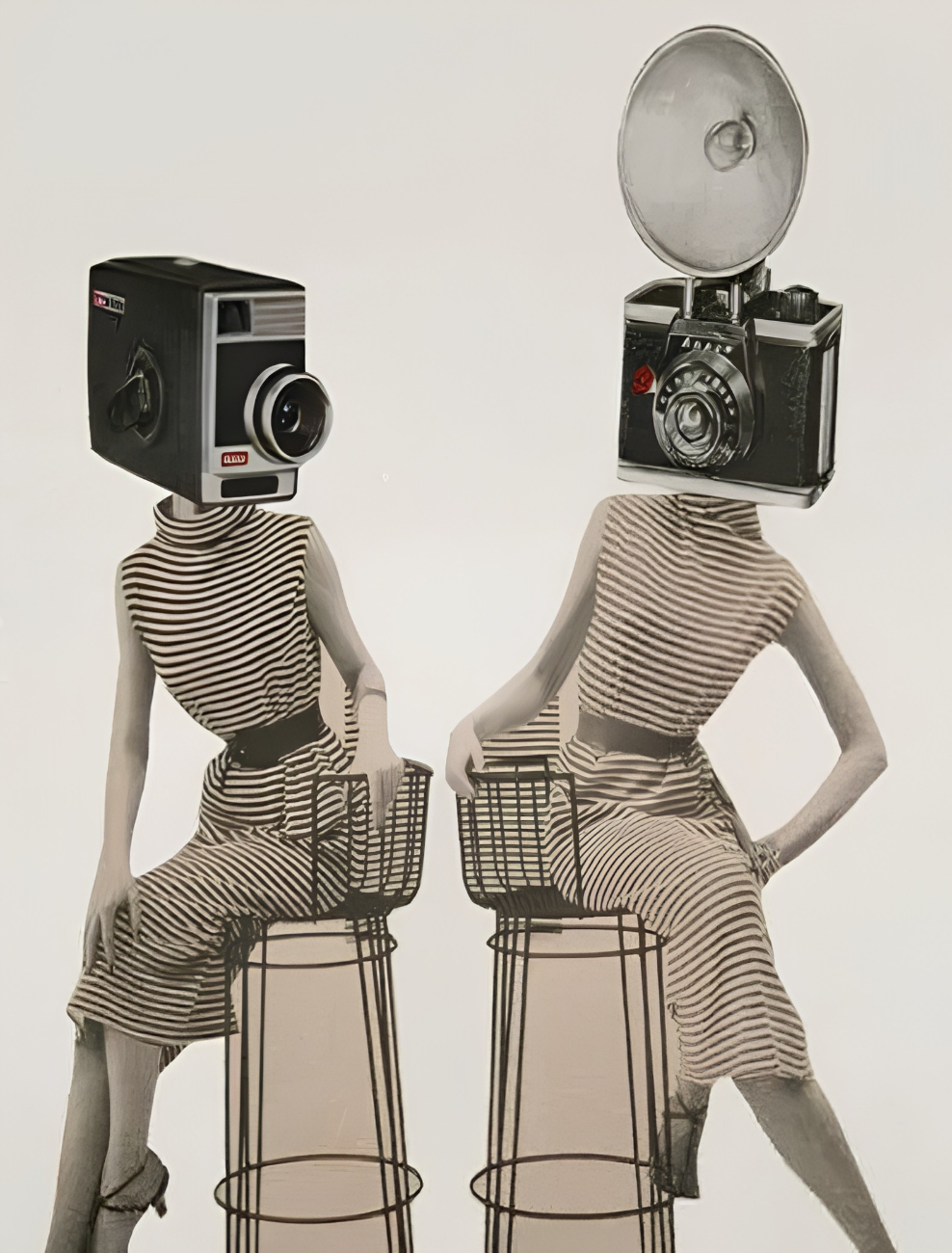 Two women with camera heads sitting on stools, wearing striped dresses, black and white, black shoes, against a plain white background.