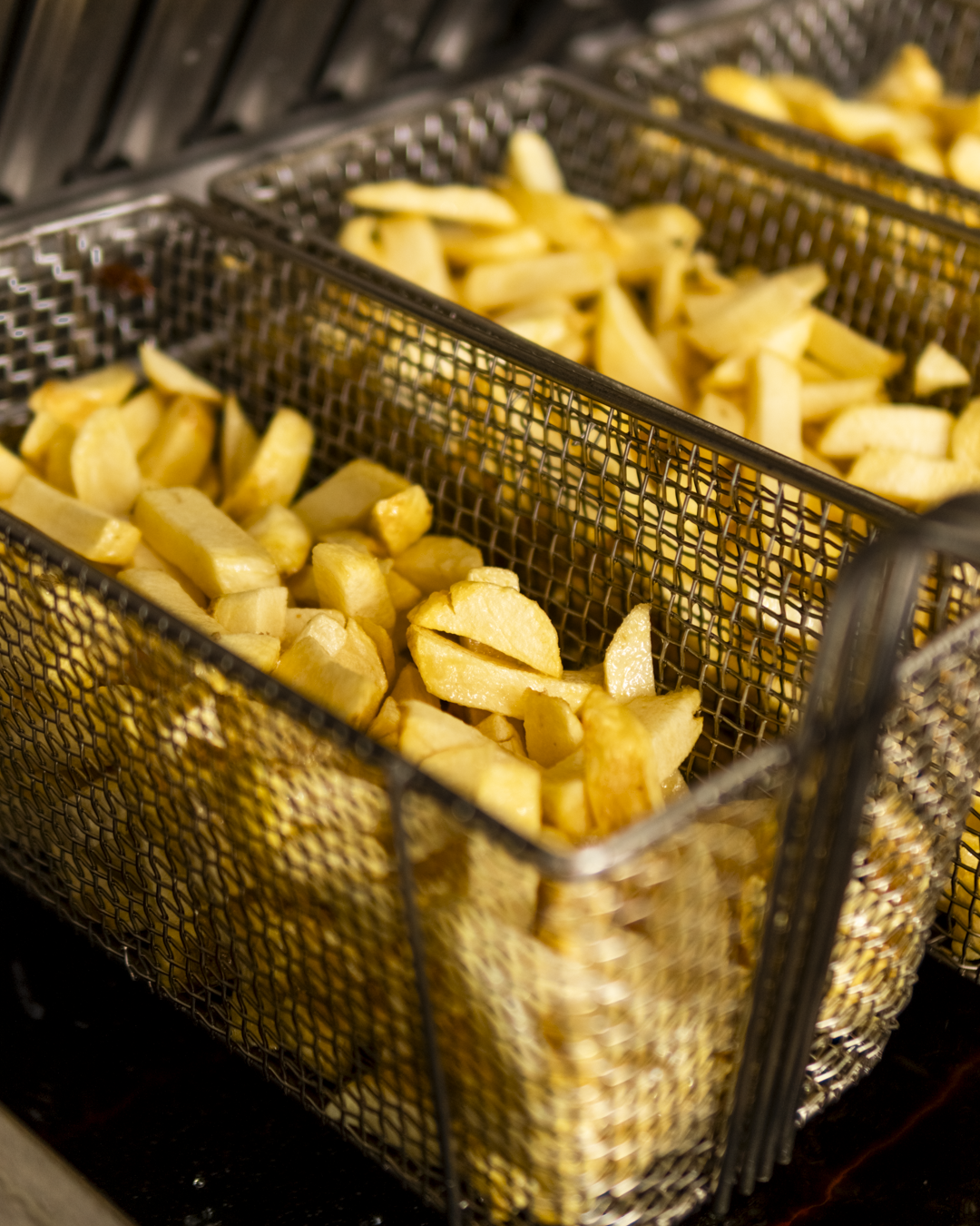 Baskets of sliced potatoes in metal wire baskets.