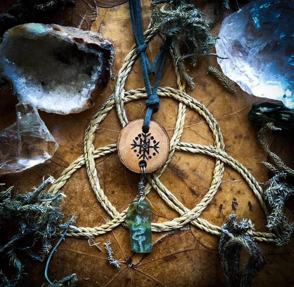 “Bindrune of Loki’s Four Direction" – Runic Talisman.  
Pyrography on conifer wood, engraved lake beach glass, metal wire, and leather.