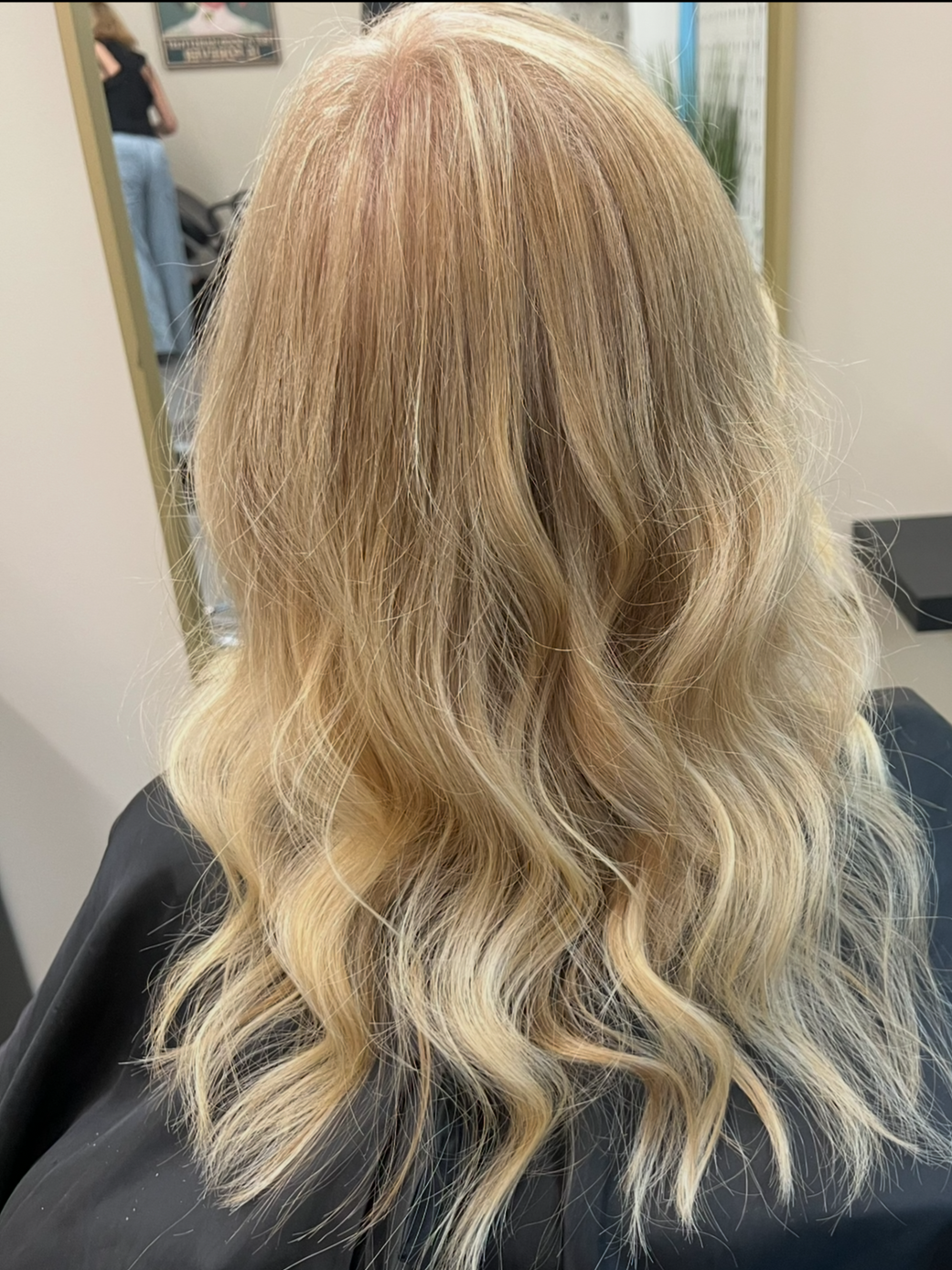 Back of a person with shoulder-length blonde hair styled in loose waves.