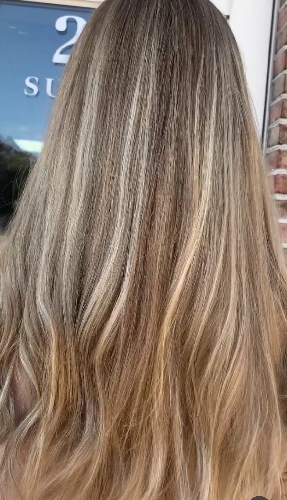 Back of a person's head with long, blonde, wavy hair.