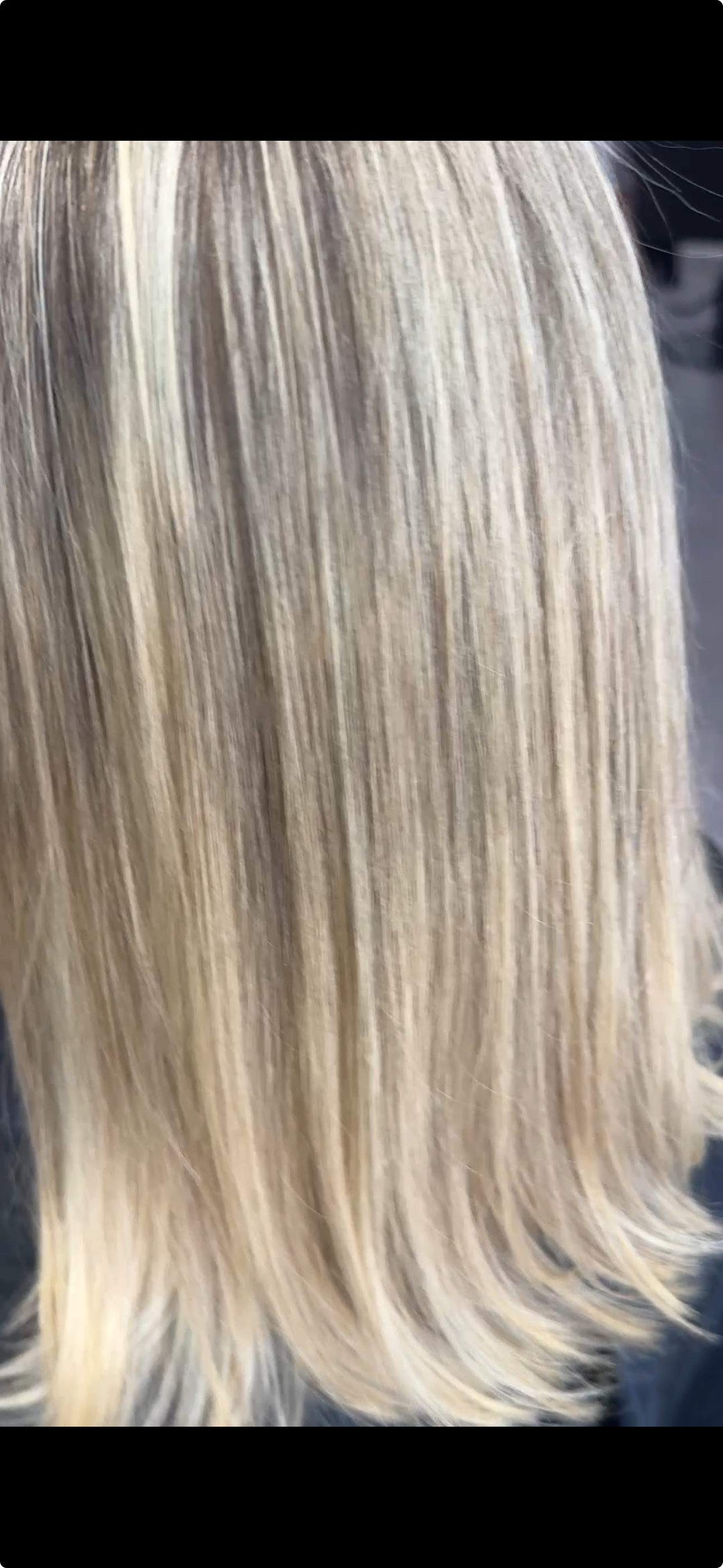 Close-up of long, straight, blonde hair with subtle highlights and soft waves at the ends.