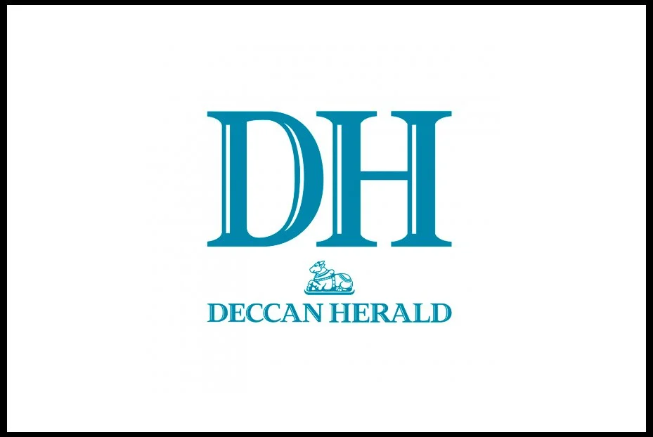 Deccan Herald logo with large blue initials 'DH' and a small emblem of a horse and rider, with 'Deccan Herald' written underneath.