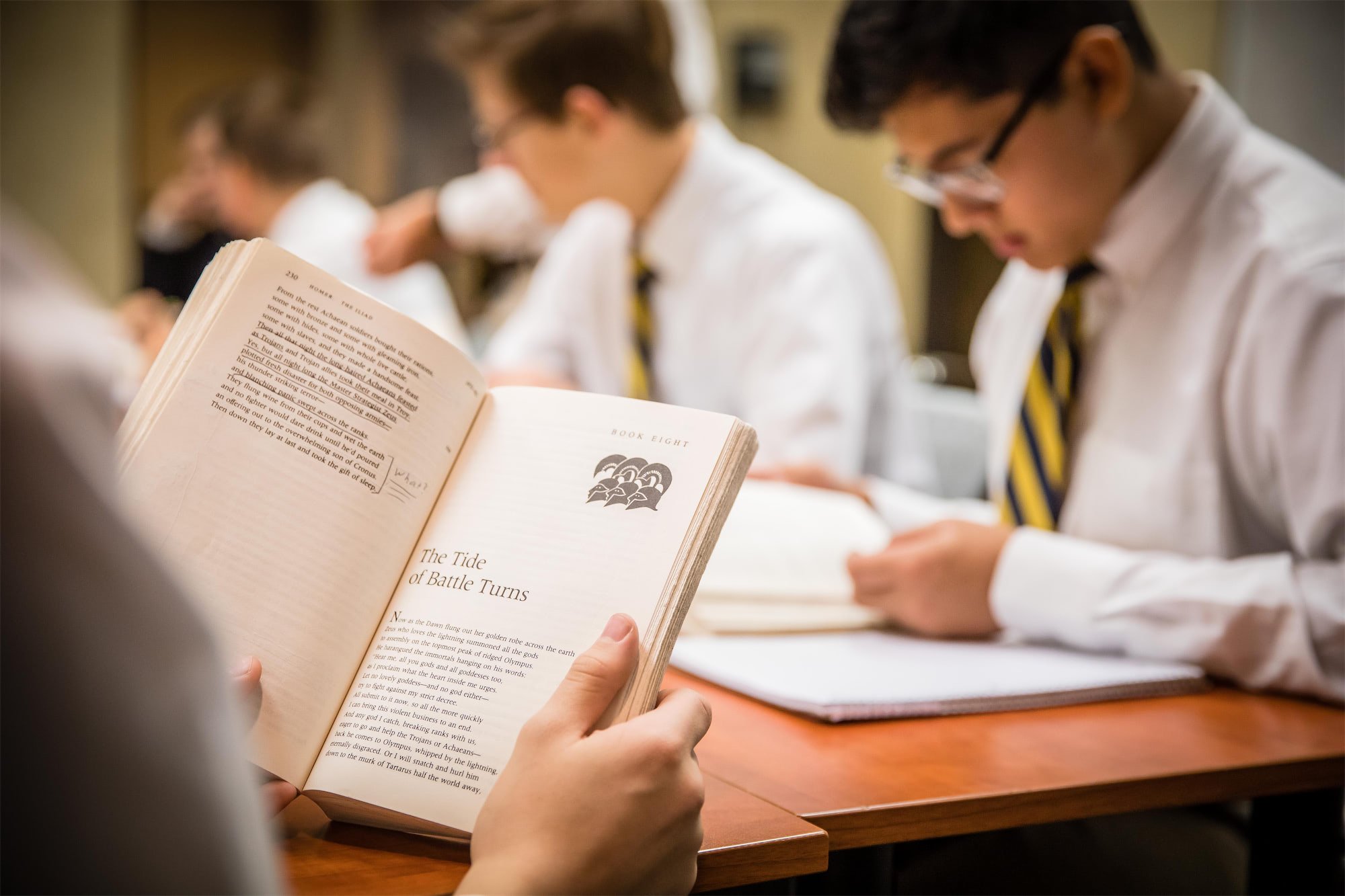 Chesterton Academy students in school uniforms reading books in a classroom.