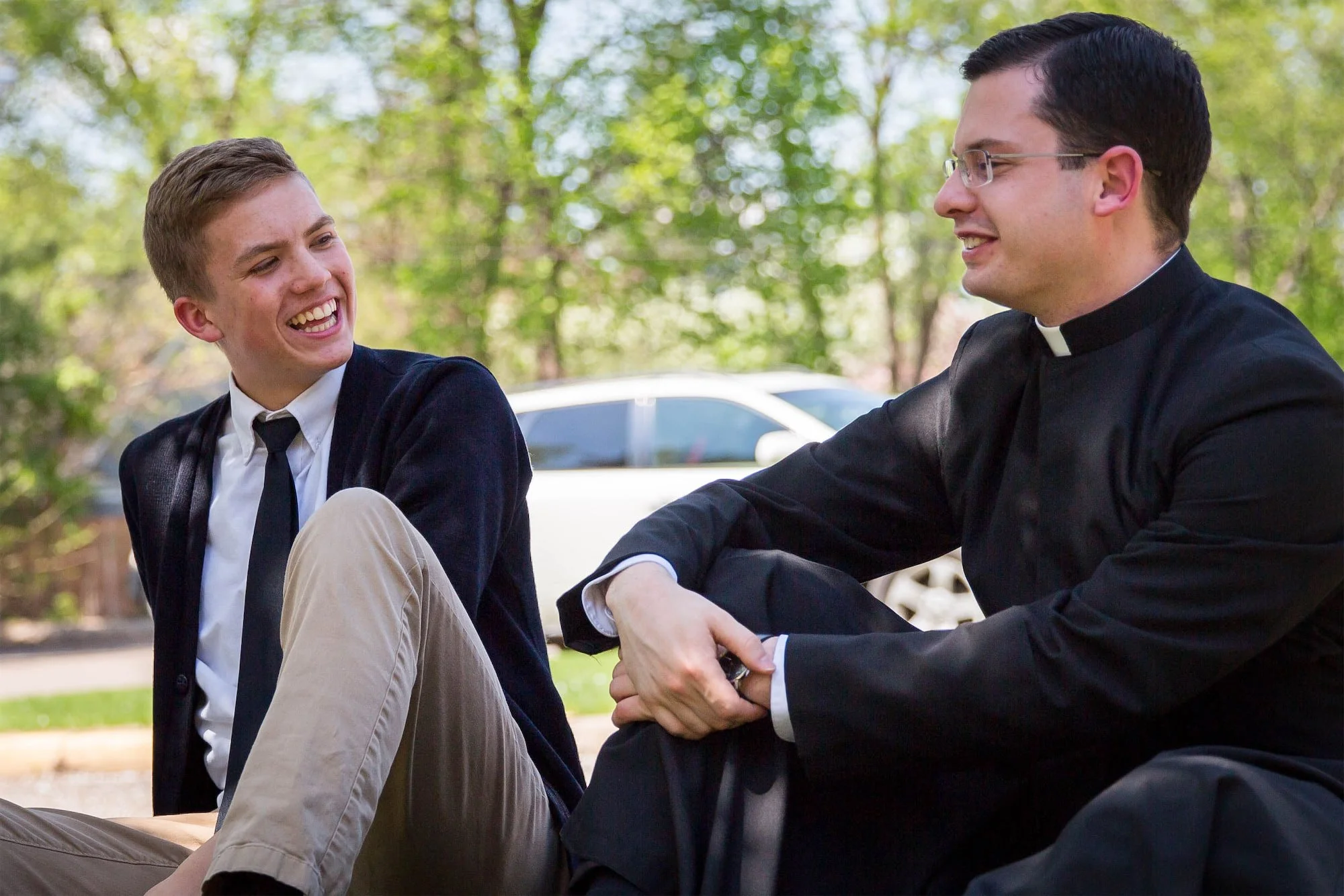 Chesterton Academy student sitting outside having a conversation with a priest.