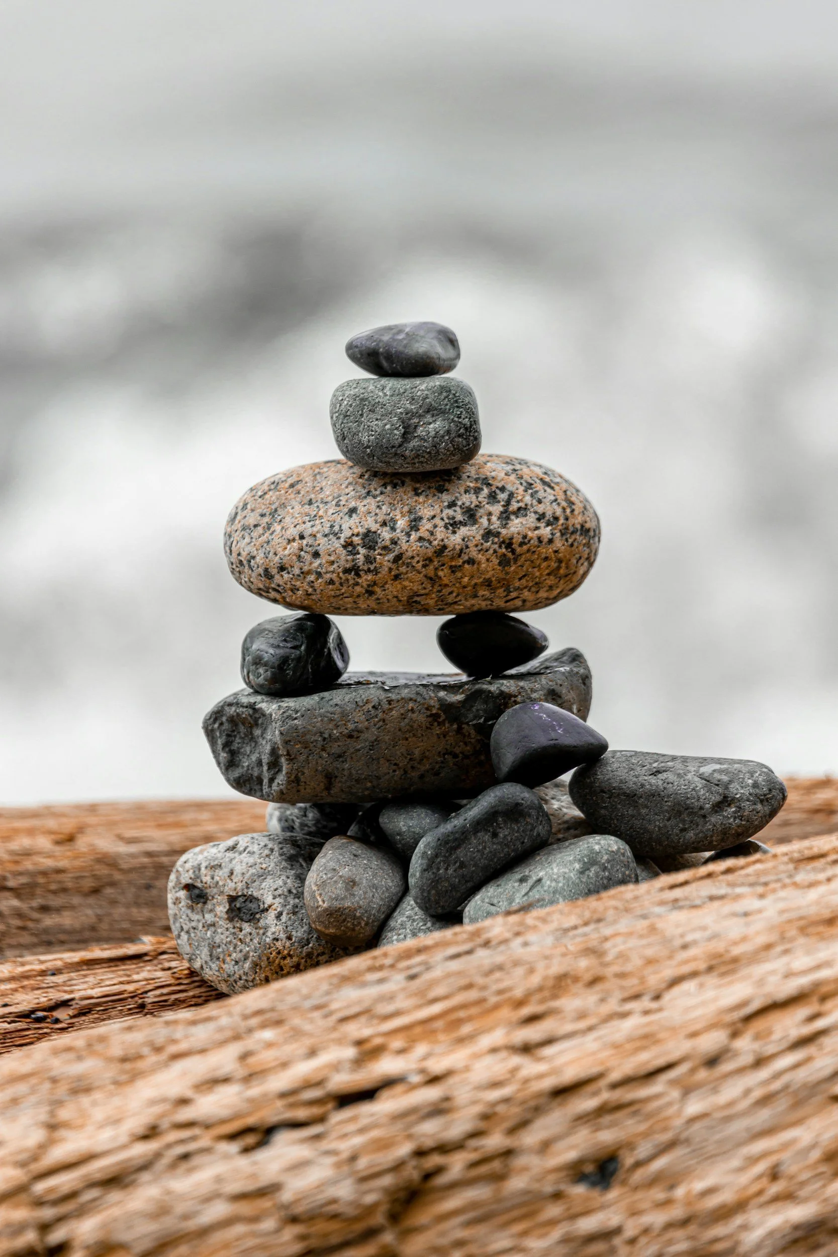 Stacked stones balanced on driftwood, symbolizing alignment and calm