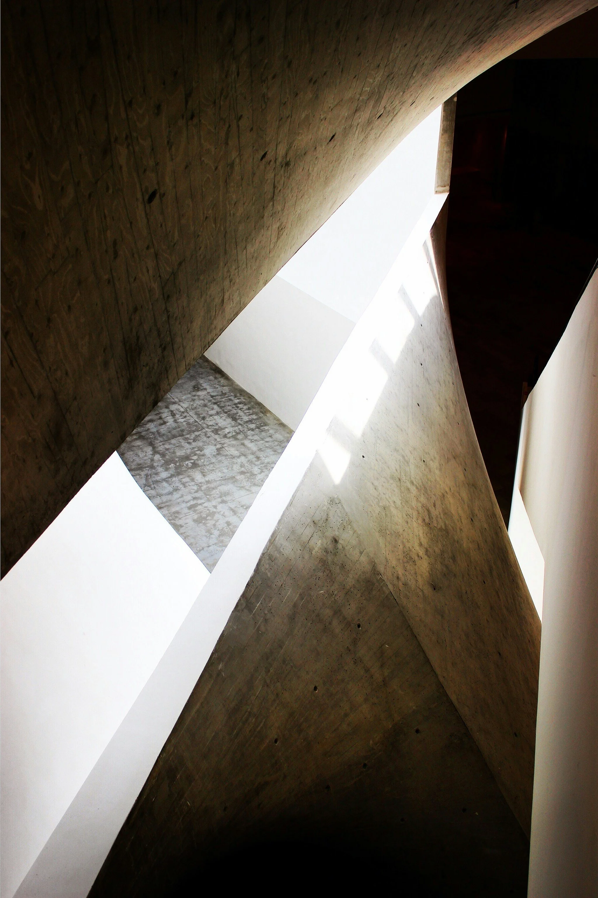 Modern architectural interior with sculptural concrete walls, warm wood, and natural light