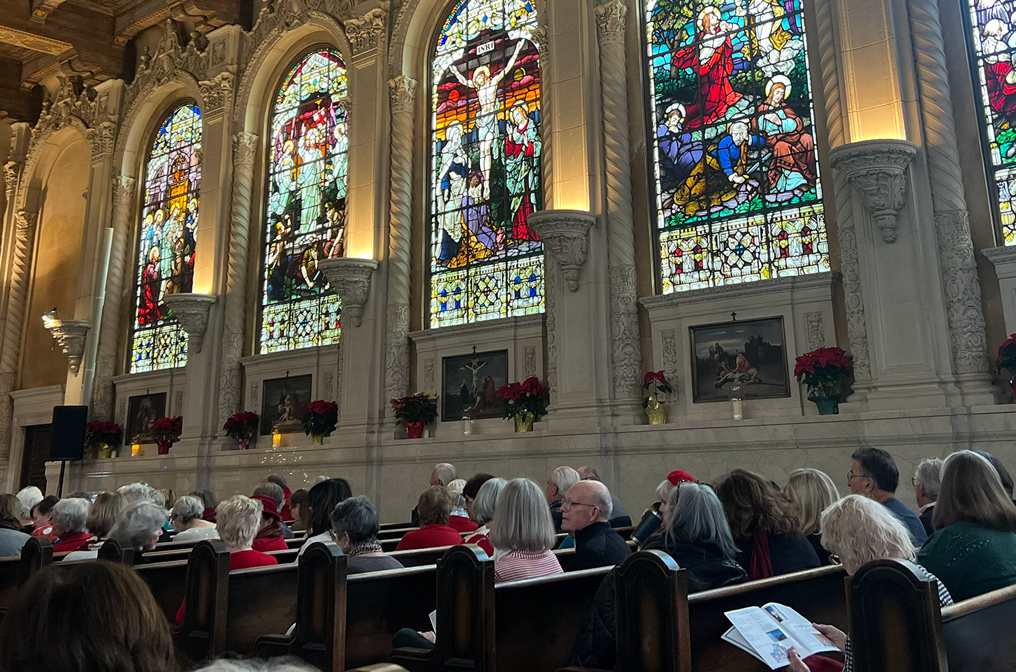 Inside the St. Vincent's Chapel with stained glass windows and people seated in pews attending an NMA concert.