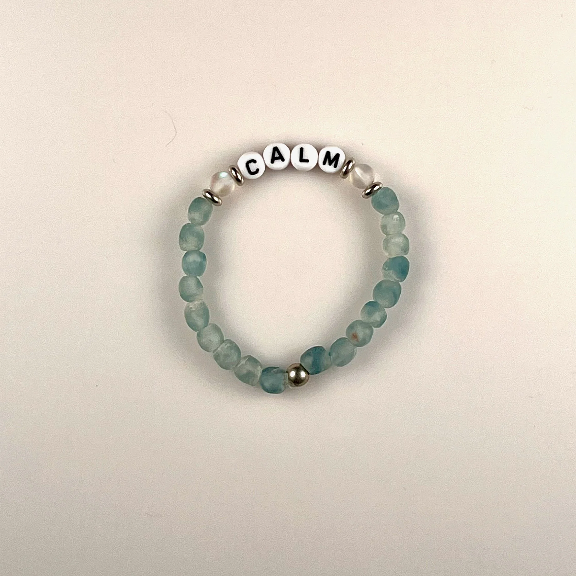 Calm: A customizable bracelet made with blue recycled glass beads, frosted clear accent beads, silver spacers and black letters on white beads. Personalize with a name or your favorite word. $25 