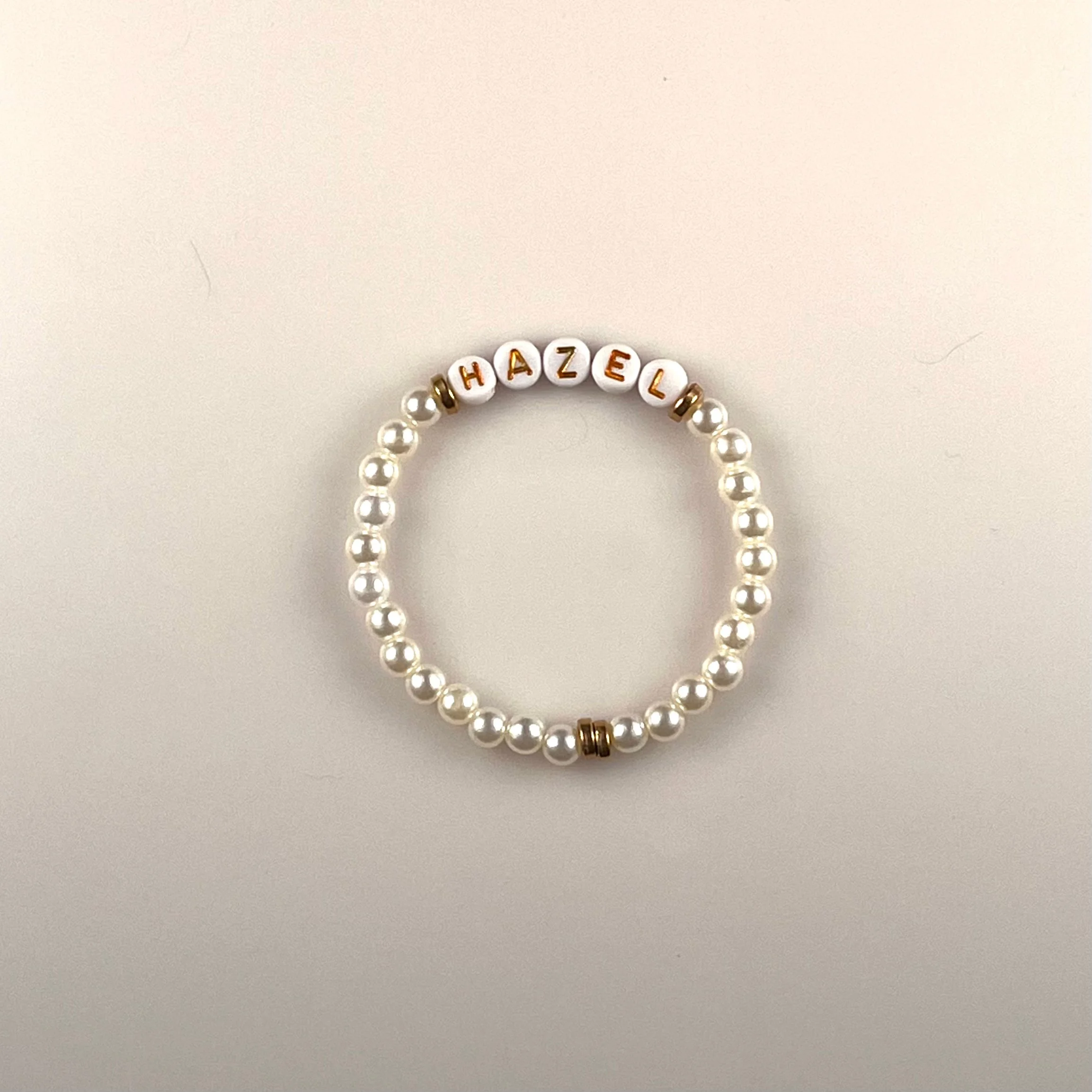 Hazel: A customizable bracelet made with pears, gold spacer beads and gold letters on white beads. Personalize with a name or your favorite word. Up to 10 letters. $25 