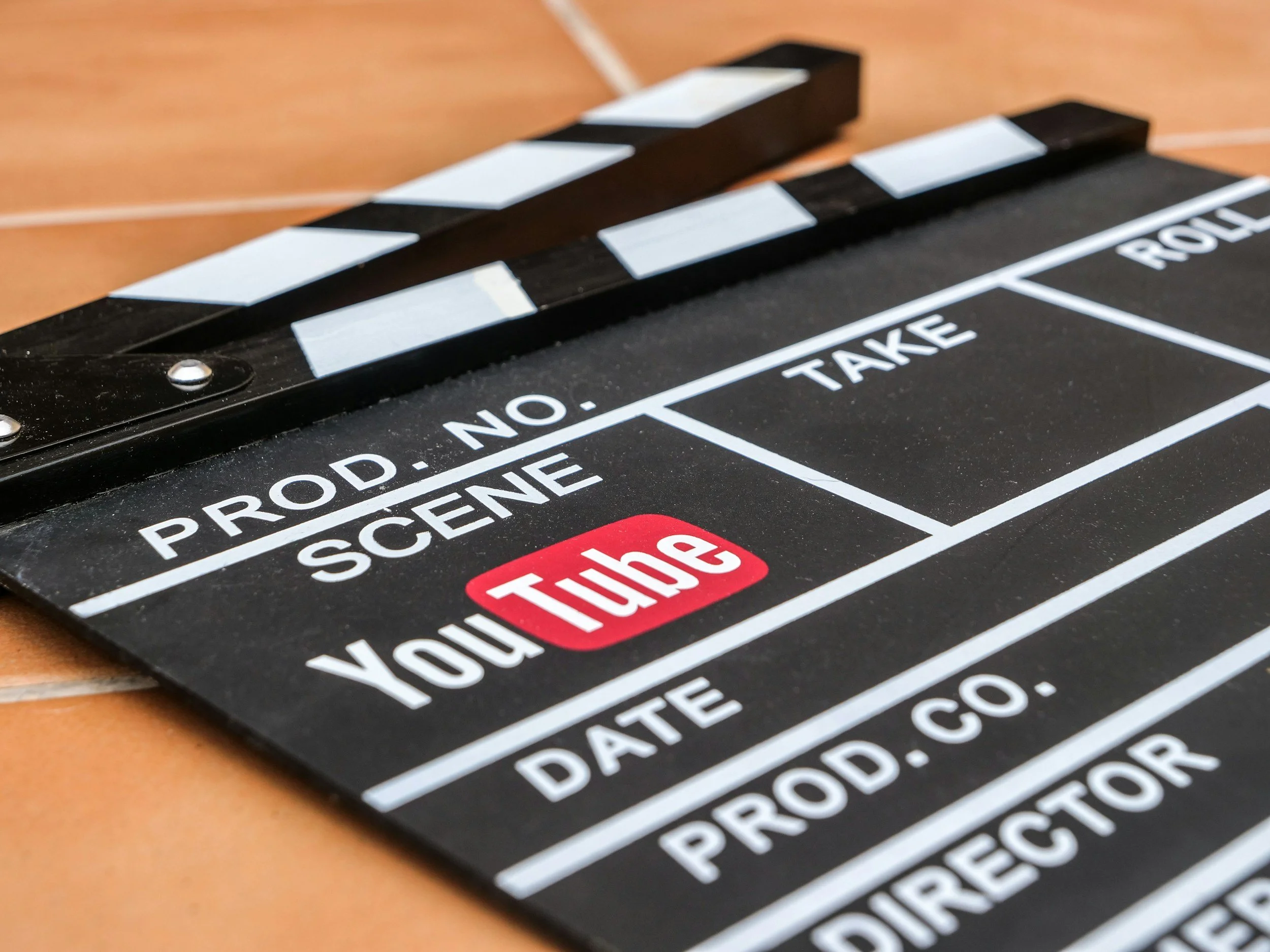 Close-up of a black film slate with white text, including 'PROD. NO.', 'SCENE', and 'TAKE', lying on a wooden surface.