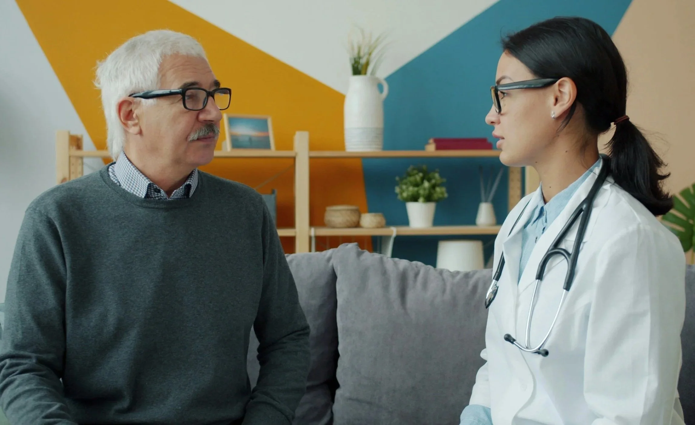 A doctor holding a stethoscope and a patient engaging in a conversation in a brightly decorated room.