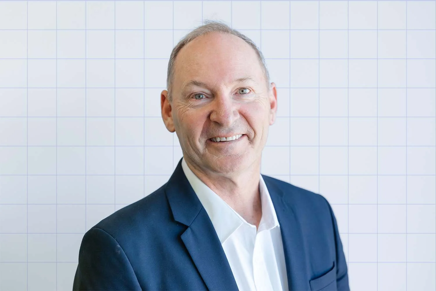 David Banfield, financial adviser at TIPS Financial Services in Perth headshot smiling wearing a dark suit and white shirt, standing in front of a grid-patterned background.
