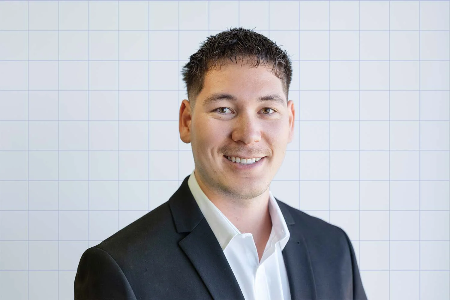 Byron Banfield, financial adviser at TIPS Financial Services in Perth portrait in a black suit and white shirt smiling against a white grid background.