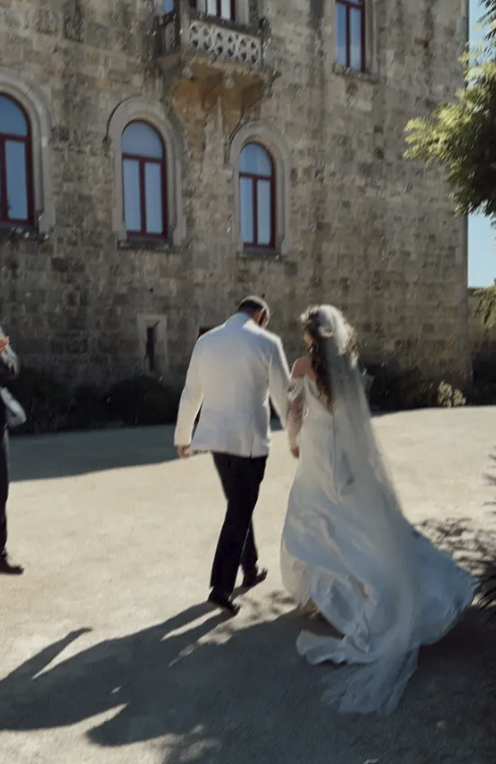 Bride and groom holding hands and walking outside a stone building during daytime.