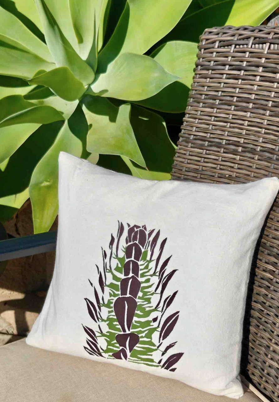 Image of original, screen printed cotton cushion with Euphorbia trigona rubra design in an outdoor setting from Handforth Botanical Studio