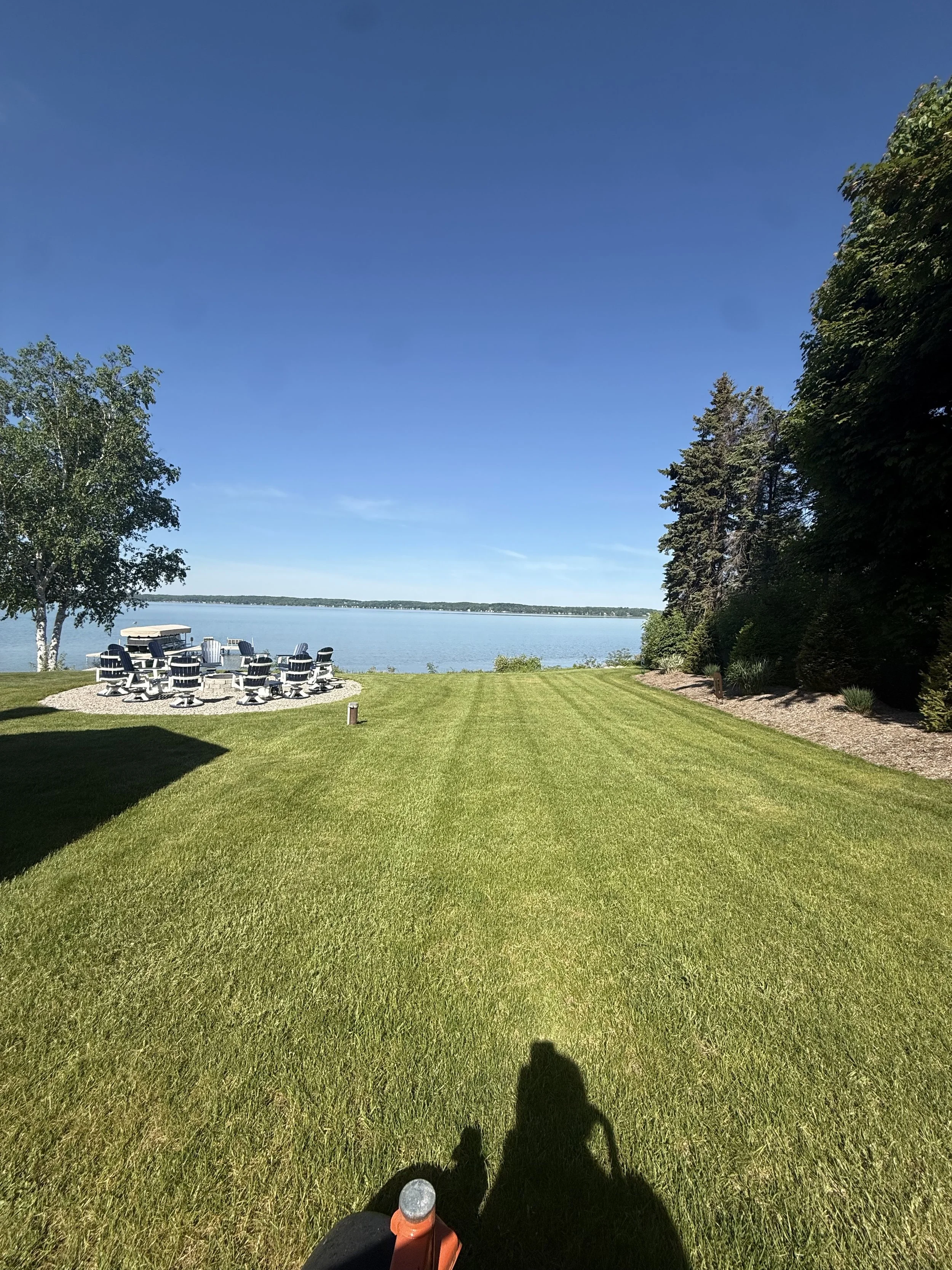 Striped waterfront lawn leading to an outdoor seating area on Torch Lake