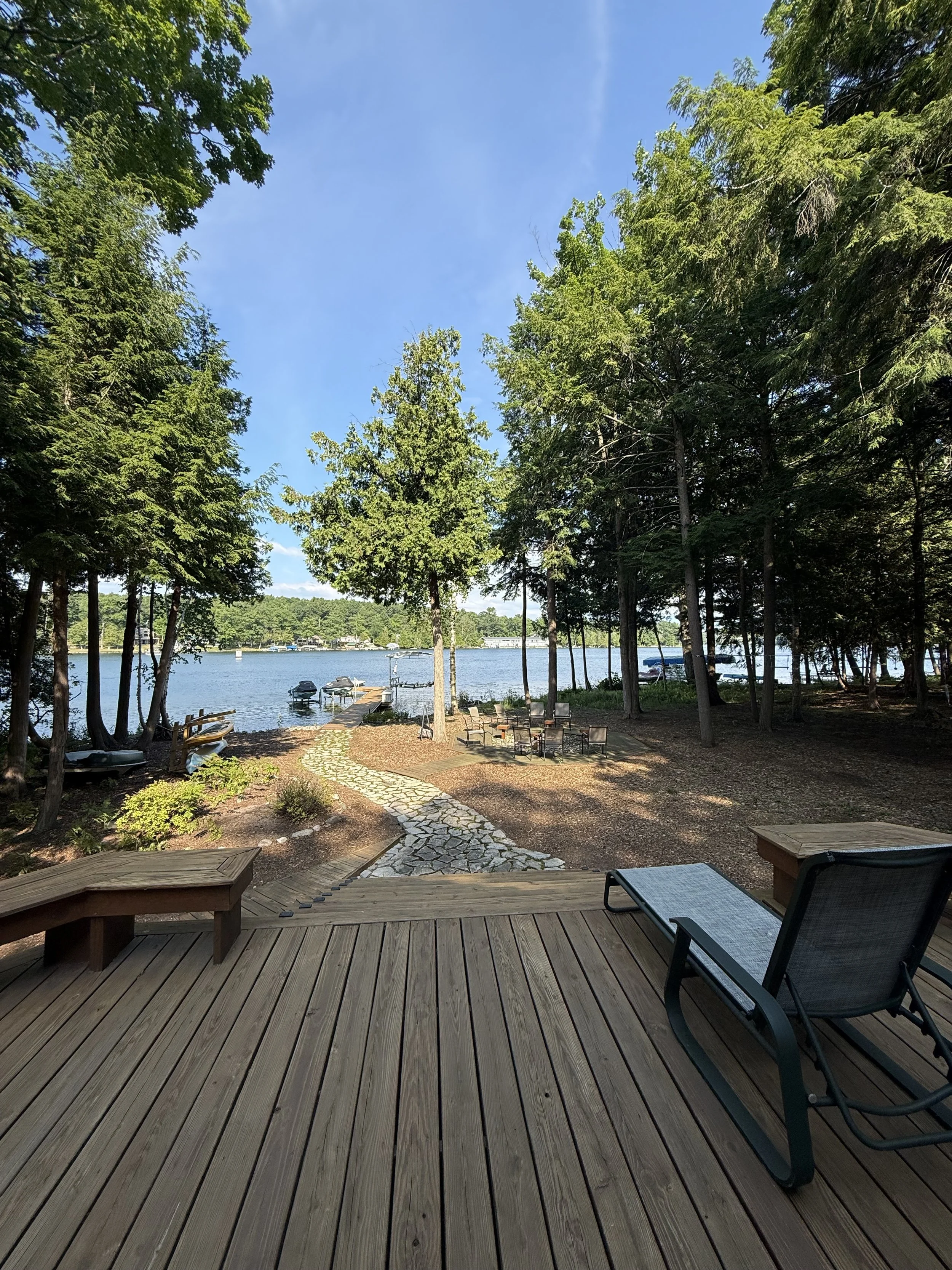 Landscaped waterfront property with a stone pathway and deck on Clam Lake