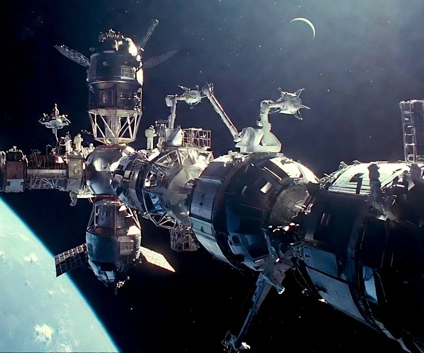 Orbital space station under construction with modular habitats, robotic arms, and Earth below — illustrating advanced in-space assembly capabilities for the Interplanetary Regen Alliance