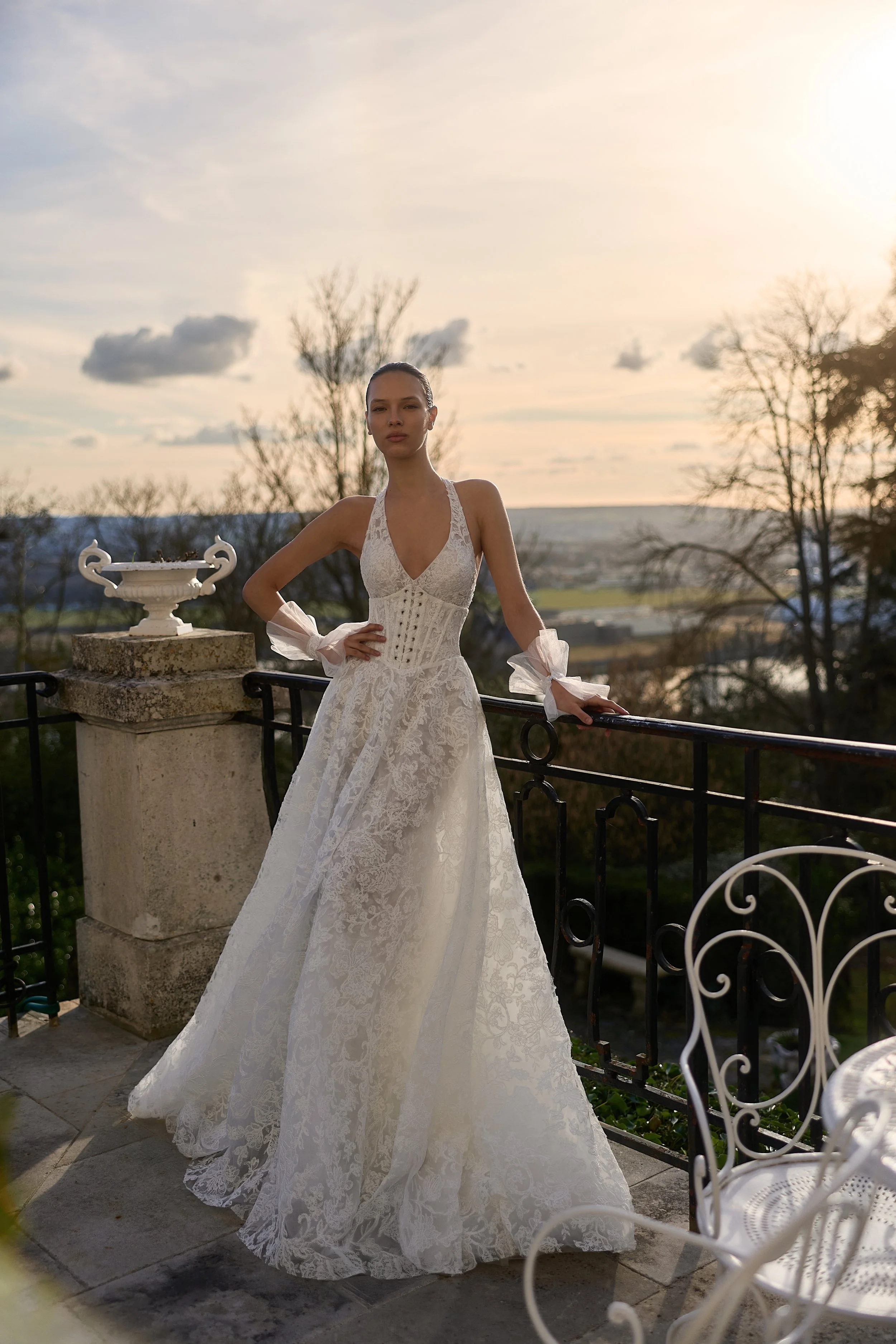 Model wearing a white lace wedding dress by Maison Yana on a sunlit garden terrace