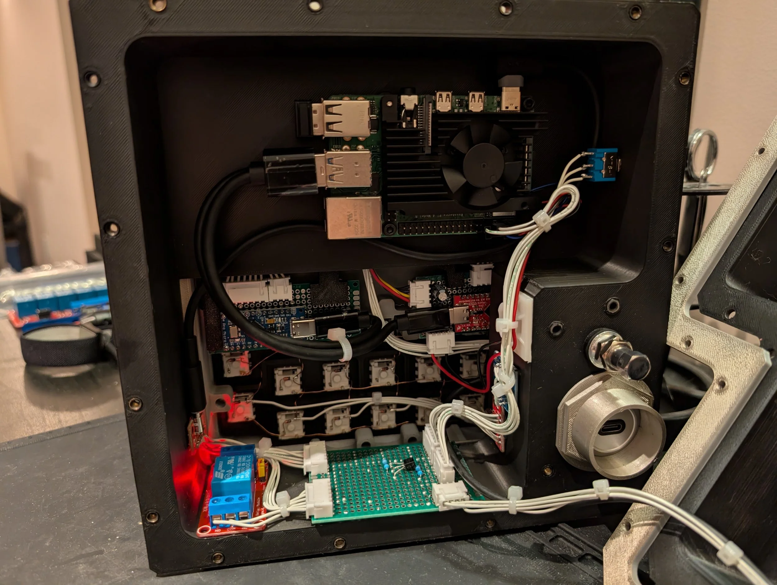 Inside a black electronic enclosure with a circuit board, black heatsink with a fan, wires, relays, and other electronic components.