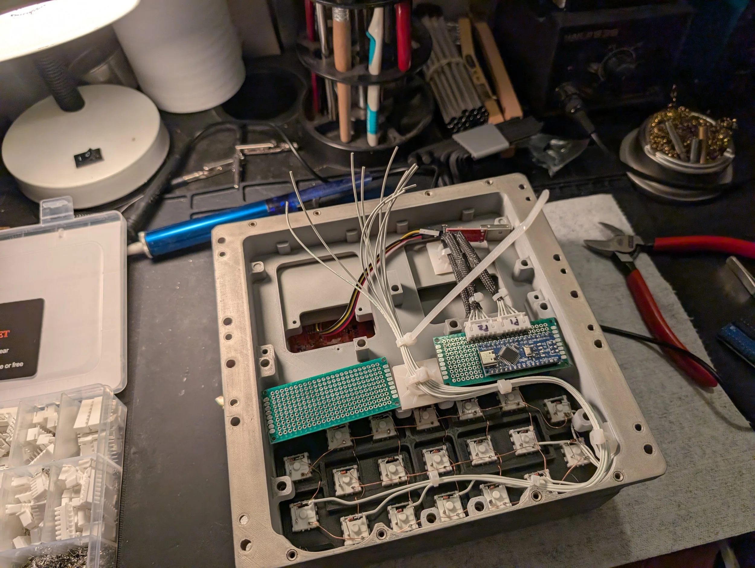 Electronic project assembly workspace with wiring, tools, and electronic components.