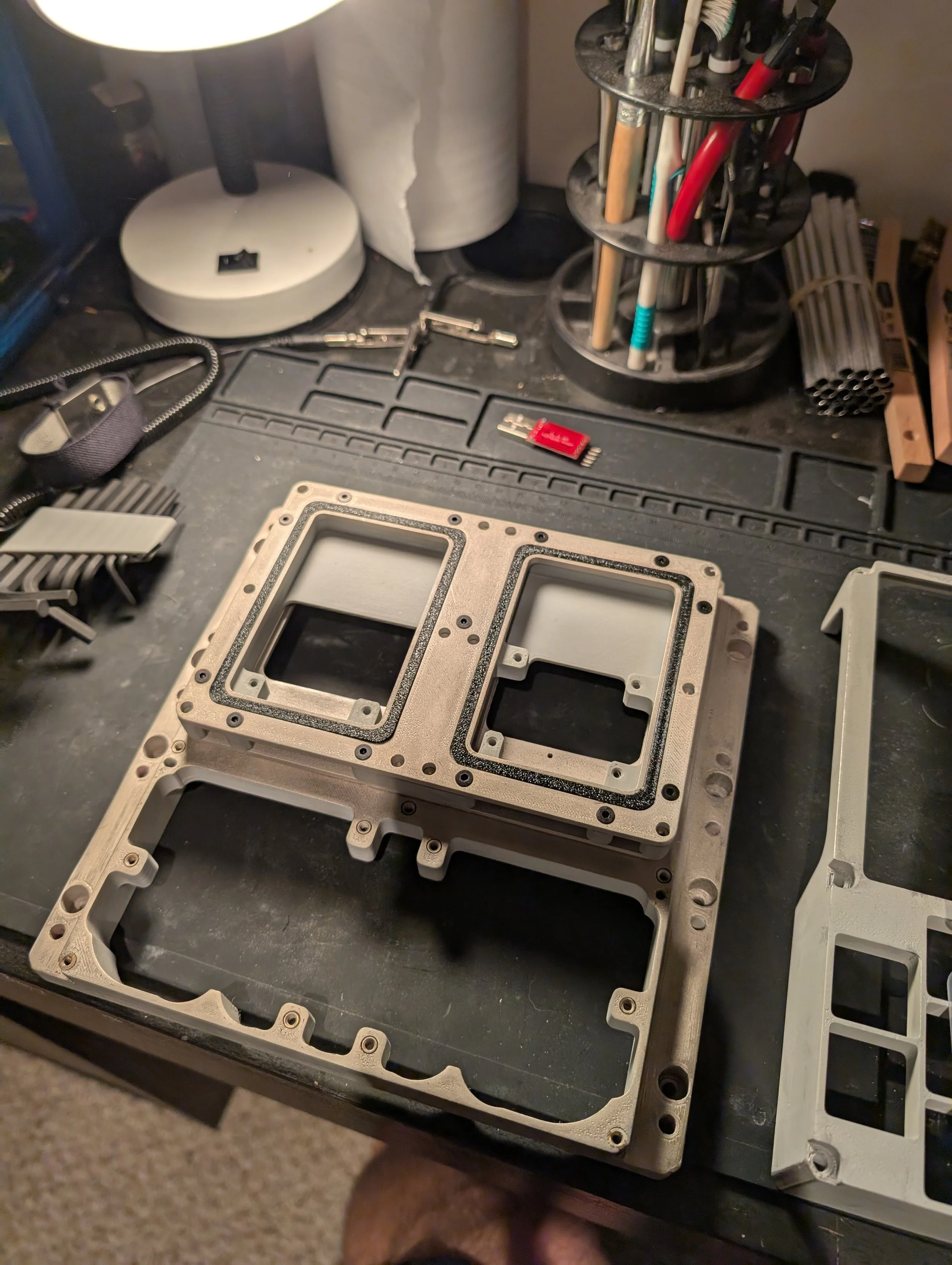 Metal computer processor frame on a black work surface with various small tools and parts around it.