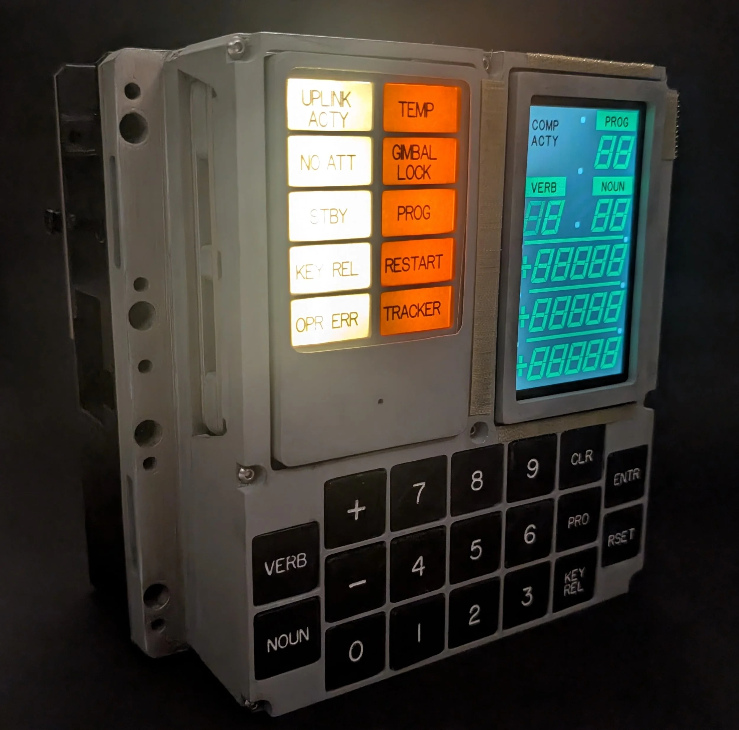 Close-up of a digital device with various colored buttons, some labeled with functions like UP/INK ACTY, NO ATT, GIMBAL LOCK, PROG, RESTART, and some with numerical labels.