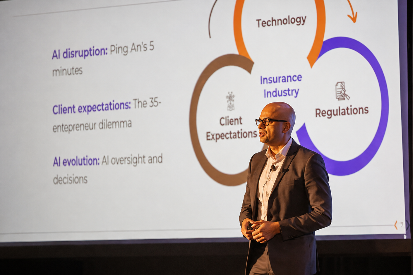 A man in a suit and glasses giving a presentation in front of a large screen displaying information about AI disruption, client expectations, AI evolution, and insurance industry regulations.