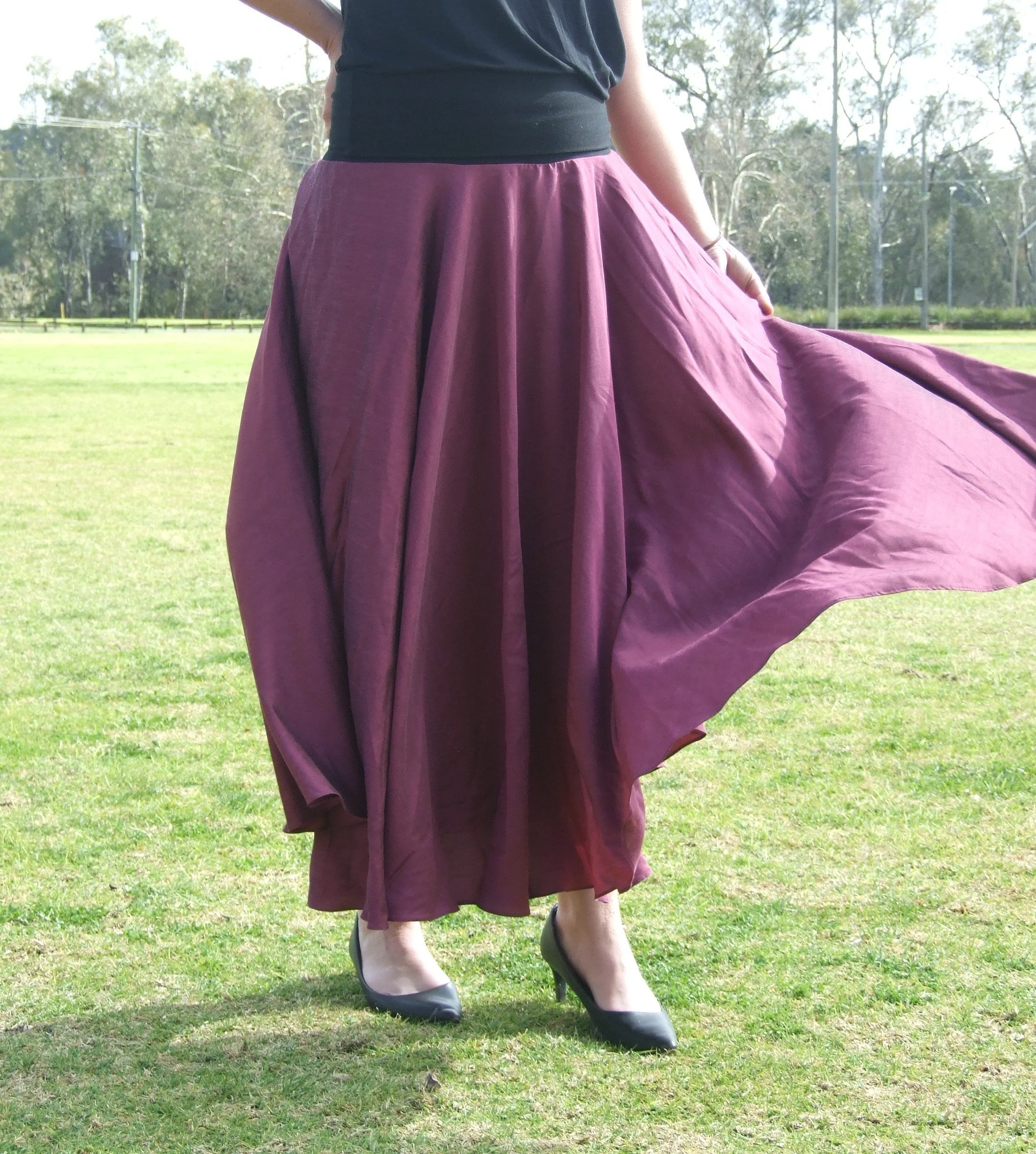 Woman wearing a Designs by Uriel Classic Circle Skirt in Midnight Rose, a fluid deep magenta fabric with a subtle sheen.