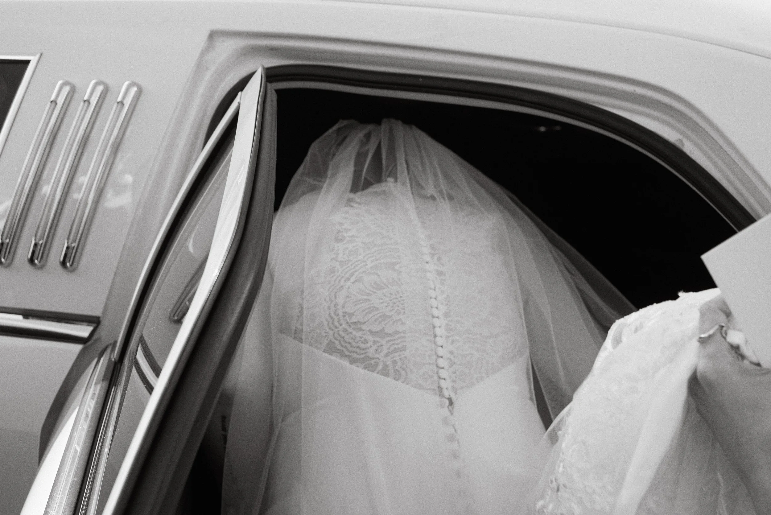 A wedding dress hanging inside a broken or cracked microwave oven, with the door open.