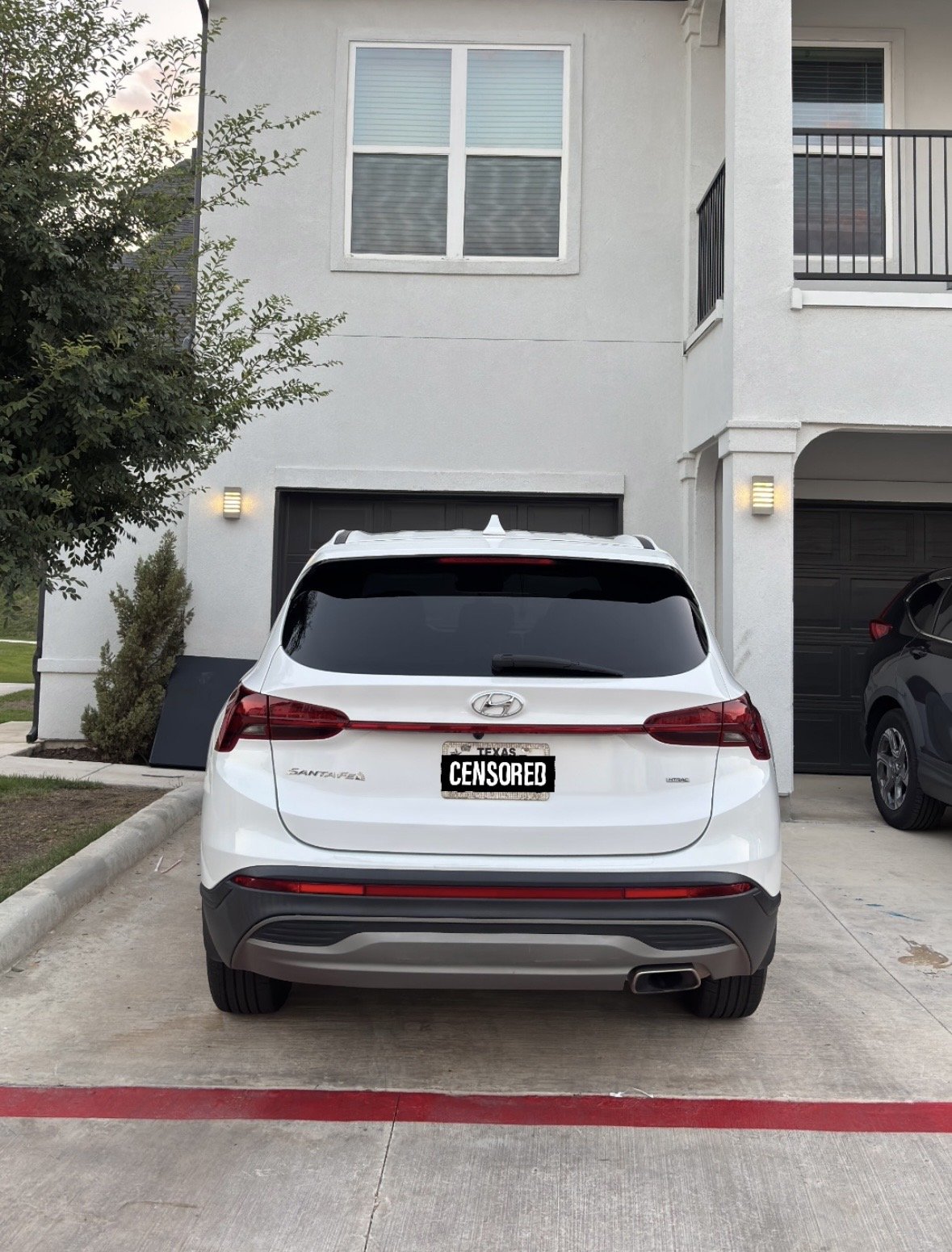 White Hyundai Santa Fe SUV parked in front of house with a censored license plate.