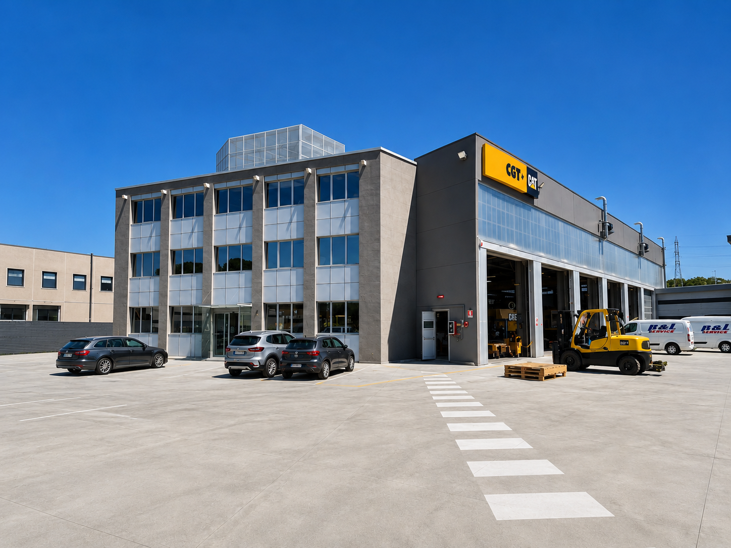 Edificio industrial con logo CGT, parcheggio con quattro auto e un rimorchio, e un muletto giallo fuori dall'officina, sotto un cielo blu chiaro.