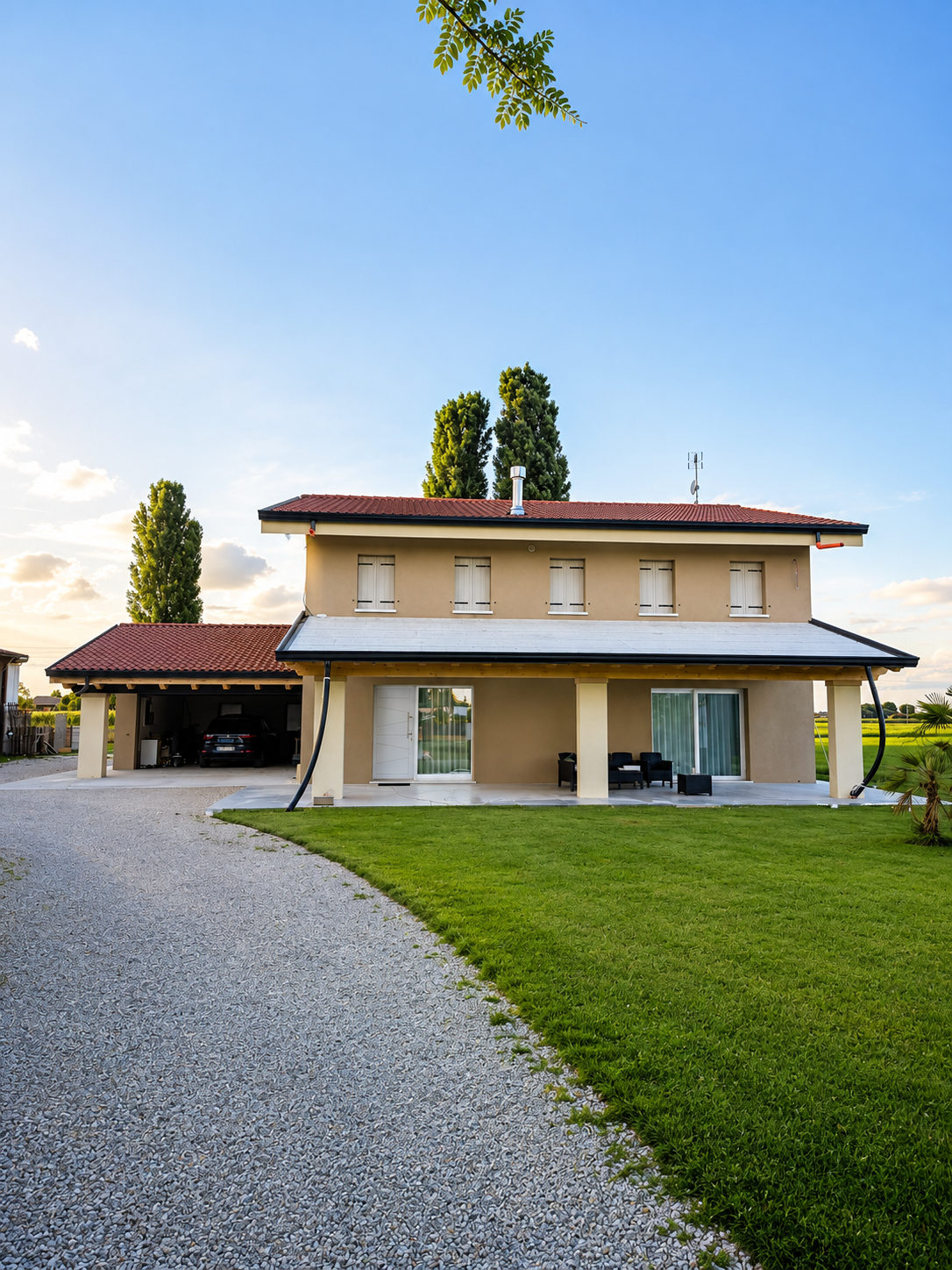 Casa moderna a due piani con cortile lastricato, garage, giardino ben curato e cielo blu.