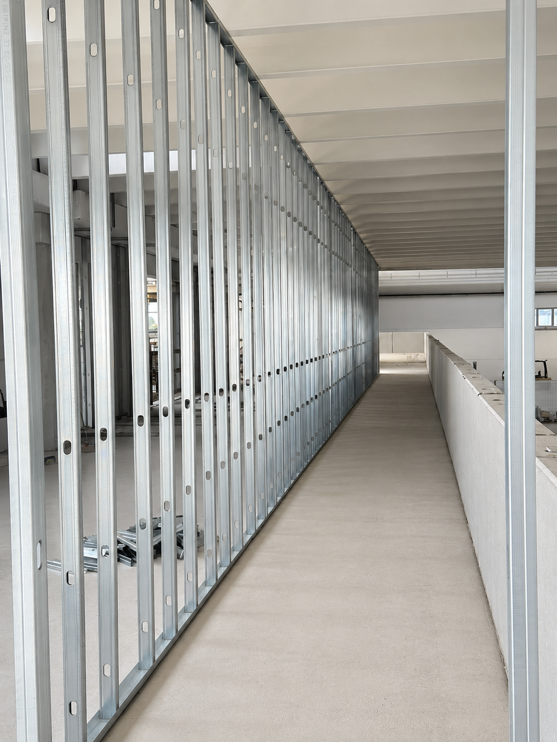 Interno di un edificio in costruzione con struttura metallica e passerella di cemento