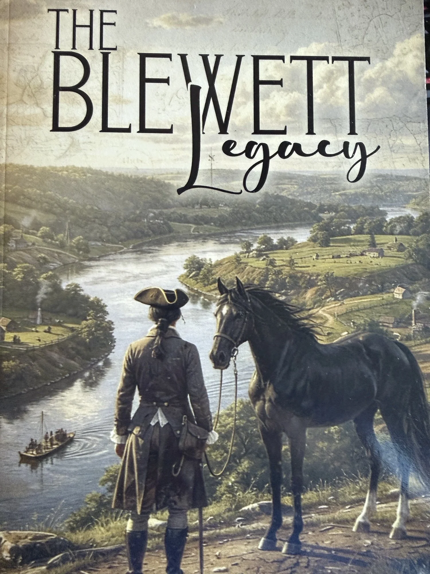 A person dressed in historical clothing standing beside a horse, overlooking a river landscape with lush greenery and distant hills, with a cloudy sky in the background. The text on the image reads 'The Blewett Legacy'.